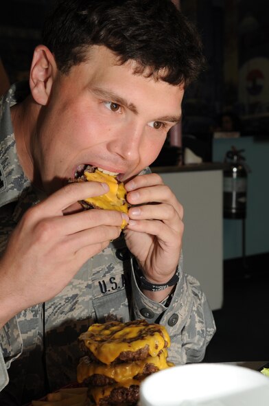 Capt. Timothy Hade, 4th Comptroller Squadron deputy budget officer, crams a cheeseburger patty into his mouth during the "Big 'A' Challenge" at Andy's Cheesesteaks and Cheeseburgers in Goldsboro, N.C., Dec. 15, 2009. If a patron finishes the meal within the 30-minute timeframe, the meal is free, otherwise the cost is $21.99. Captain Hade is originally from Franklin Lakes, N.J. (U.S. Air Force photo/Staff Sgt. Courtney Richardson)