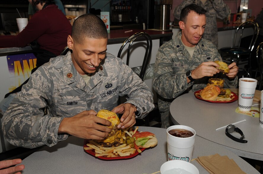 Maj. Anthony Smith, 4th Comptroller Squadron commander, and Lt. Col. Michael Vecera, 4th Fighter Wing staff judge advocate, strategize a way to attack the "Big 'A' Challenge" at Andy's Cheesesteaks and Cheeseburgers in Goldsboro, N.C., Dec. 15, 2009. Along with two other officers Maj. Smith and Col. Vecera attempted to consume a 50-ounce stack of cheeseburgers, fries and 24-ounce beverage within 30 minutes. Maj. Smith is originally from Vincenza, Italy, and Col. Vecera is a Baltimore native. (U.S. Air Force photo/Staff Sgt. Courtney Richardson)