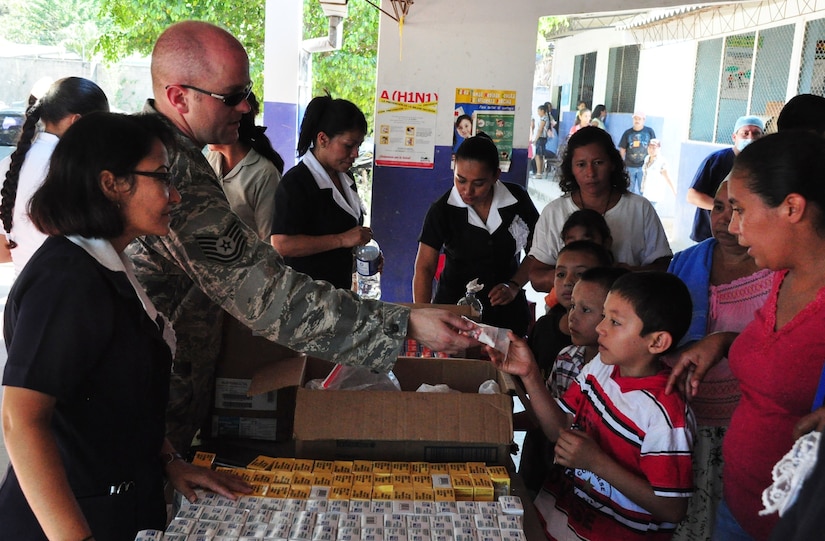 U.S. Air Force Tech. Sgt. Bryan Mayer and a representative of the Salvadoran Ministry of Health distribute vitamins and hygiene items to local residents in the town of El Achiotal Dec. 15, 2009, during a Medical Civil Action Program (MEDCAP) here. The two-day medical mission offered residents affected by November flooding and mudslides the opportunity to receive medical care, immunizations, education, and prescription drugs free of charge. It was a combined effort between the Salvadoran government, the U.S. Embassy in El Salvador, and U.S. Southern Command’s Joint Task Force-Bravo – based at Soto Cano Air Base, Honduras. More than 1,300 patients were seen in the two days. (U.S. Air Force photo/Tech. Sgt. Mike Hammond)