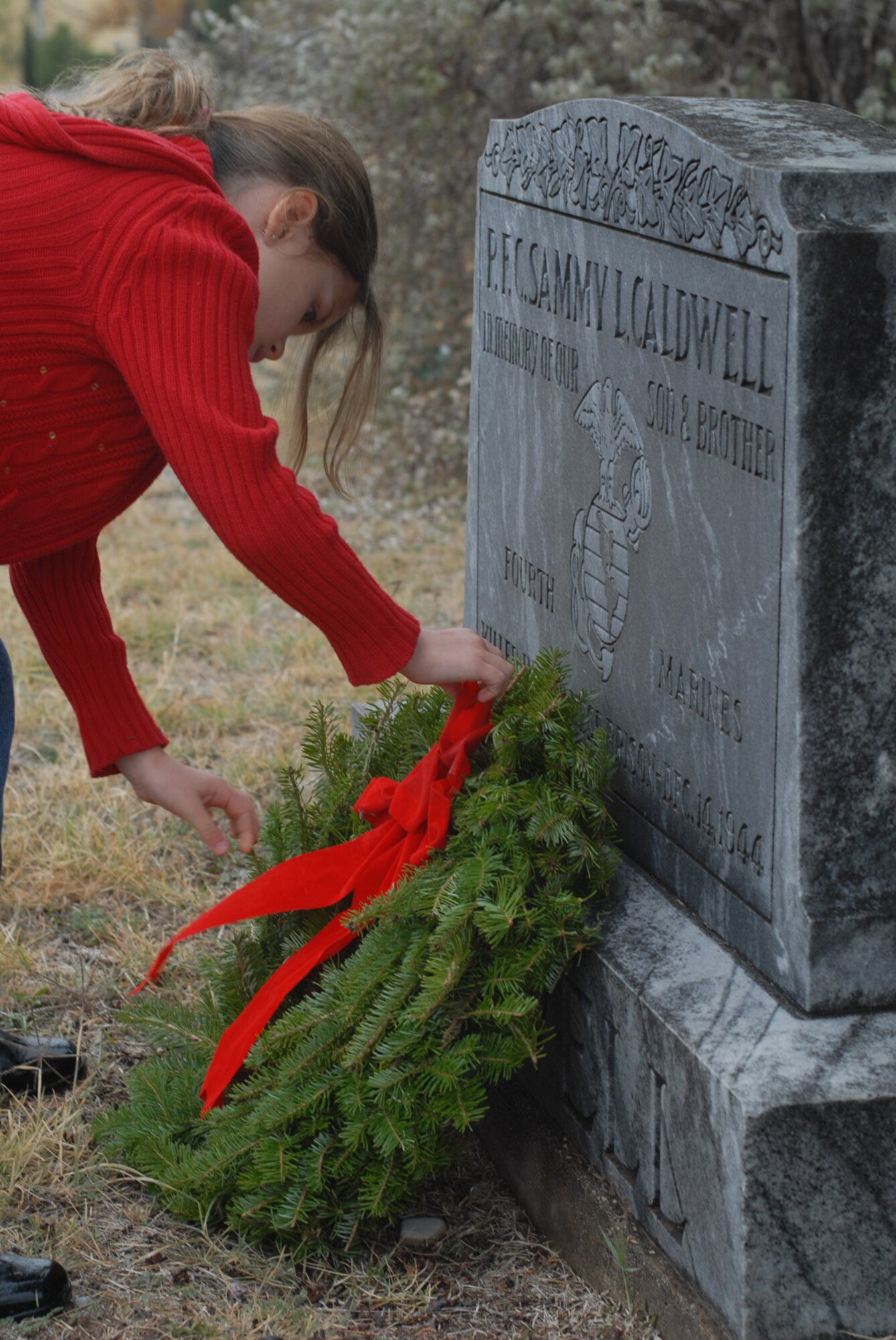 SAN ANGELO, Texas -- Emily DeSantis, 7, lays a wreath on a veteran's grave during the Civil Air Patrol's annual Wreaths Across America event at Belvedere Memorial Park, Dec. 12, 2009. This event honors the courage and sacrifice of veterans of the Armed Forces and the Merchant Marine. Emily is the daughter of Senior Master Sgt. Annette Whitenack, 17th Medical Group, and Master Sgt. Thomas DeSantis, 315th Training Squadron, Goodfellow Air Force Base, Texas. (U.S. Air Force photo/Staff Sgt. Laura R. McFarlane)
