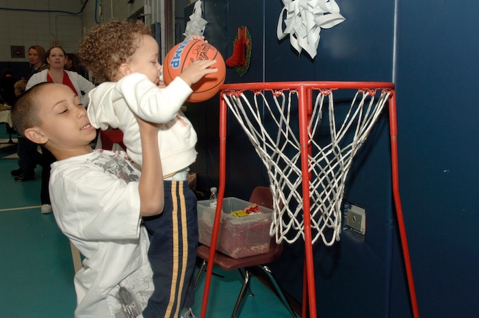 Donte Christopher lifts Brandon Christopher to help him make a basket for a prize during the youth holiday party at the Youth Programs Center here Dec. 12, 2009. Charleston Air Force Base youths had the opportunity to play games, decorate cupcakes, scale a wall, sit on Santa's lap and enjoy arts and crafts during the annual holiday party. Brandon and Donte are the sons of U.S. Air Force Tech. Sgt. Charles Christopher who is with the 437th Maintenance Squadron. (U.S. Air Force photo/Staff Sgt. Marie Brown)