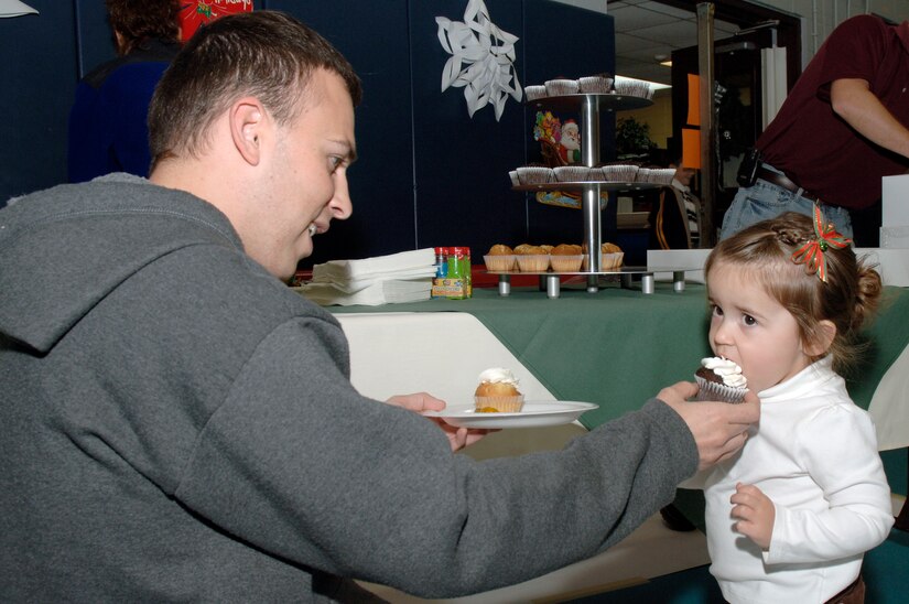 U.S. Air Force Staff Sgt. Robert Walker helps his daughter Hayden take a bite of a cupcake during the youth holiday party at the Youth Programs Center here Dec. 12, 2009. Charleston Air Force Base youths had the opportunity to play games, decorate cupcakes, scale a wall, sit on Santa's lap and enjoy arts and crafts during the annual holiday party. Sergeant Walker is a loadmaster assigned to the 15th Airlift Squadron. (U.S. Air Force photo/Staff Sgt. Marie Brown)