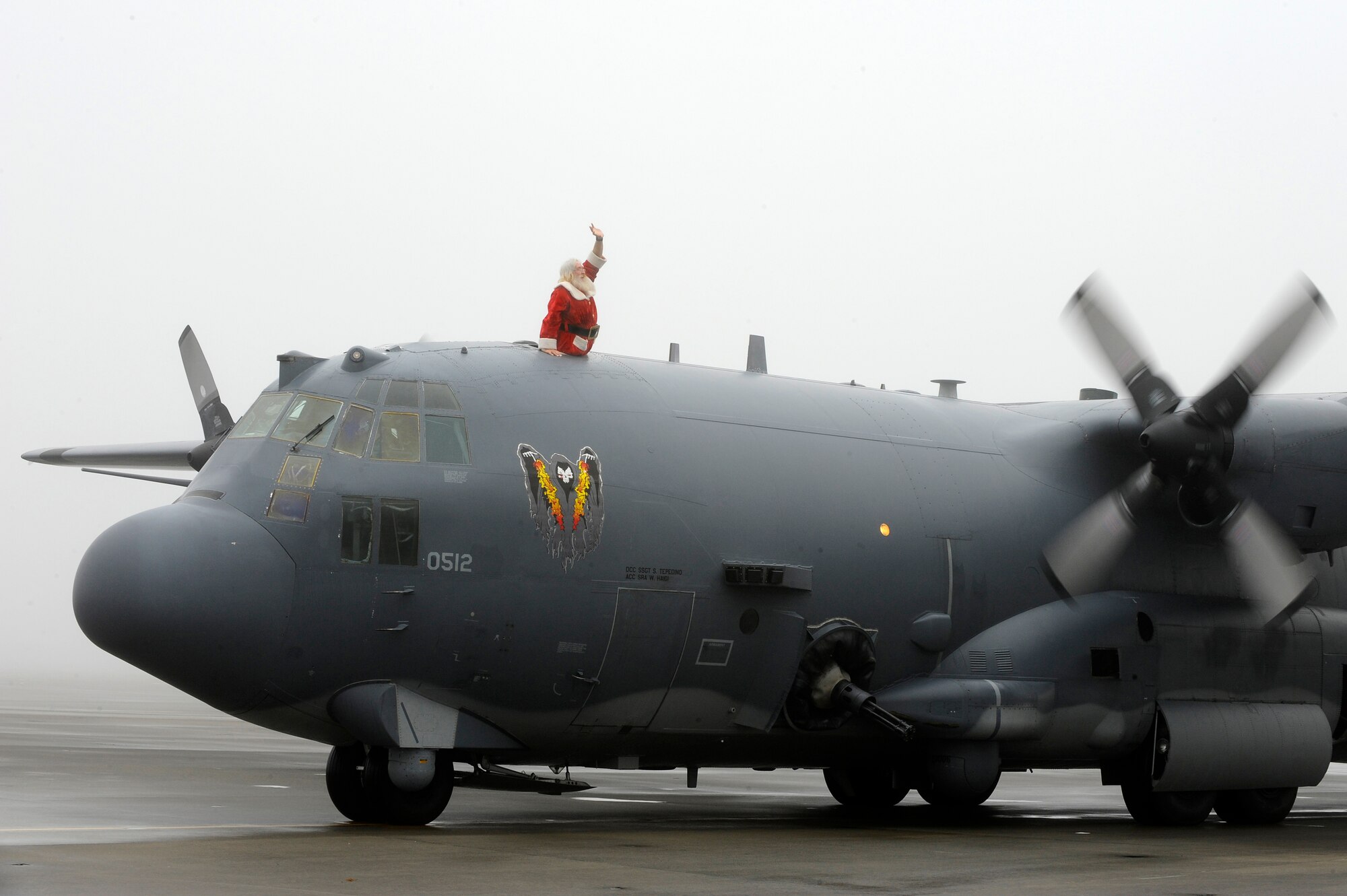 Santa Claus waves to children from an AC-130U Spooky gunship on the flightline at Hurlburt Field Dec. 13. He later handed out presents and posed for pictures with the children who came out to watch his arrival.  (Air Force photo by Senior Airman Jason Epley/Released)