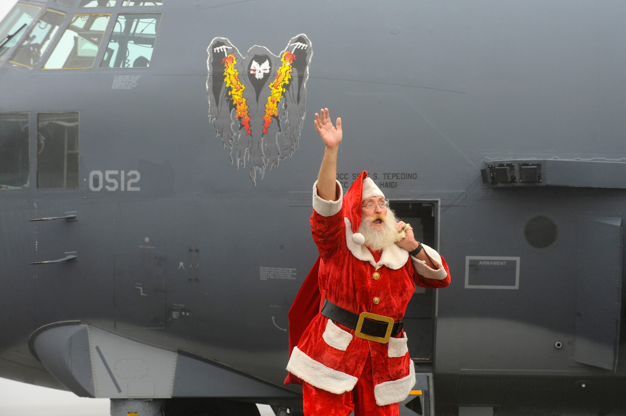 Santa Claus waves to children after exiting an AC-130U Spooky gunship on the flightline at Hurlburt Field Dec. 13. He later handed out presents and posed for pictures with the children who came out to watch his arrival.  (Air Force photo by Senior Airman Jason Epley/Released)