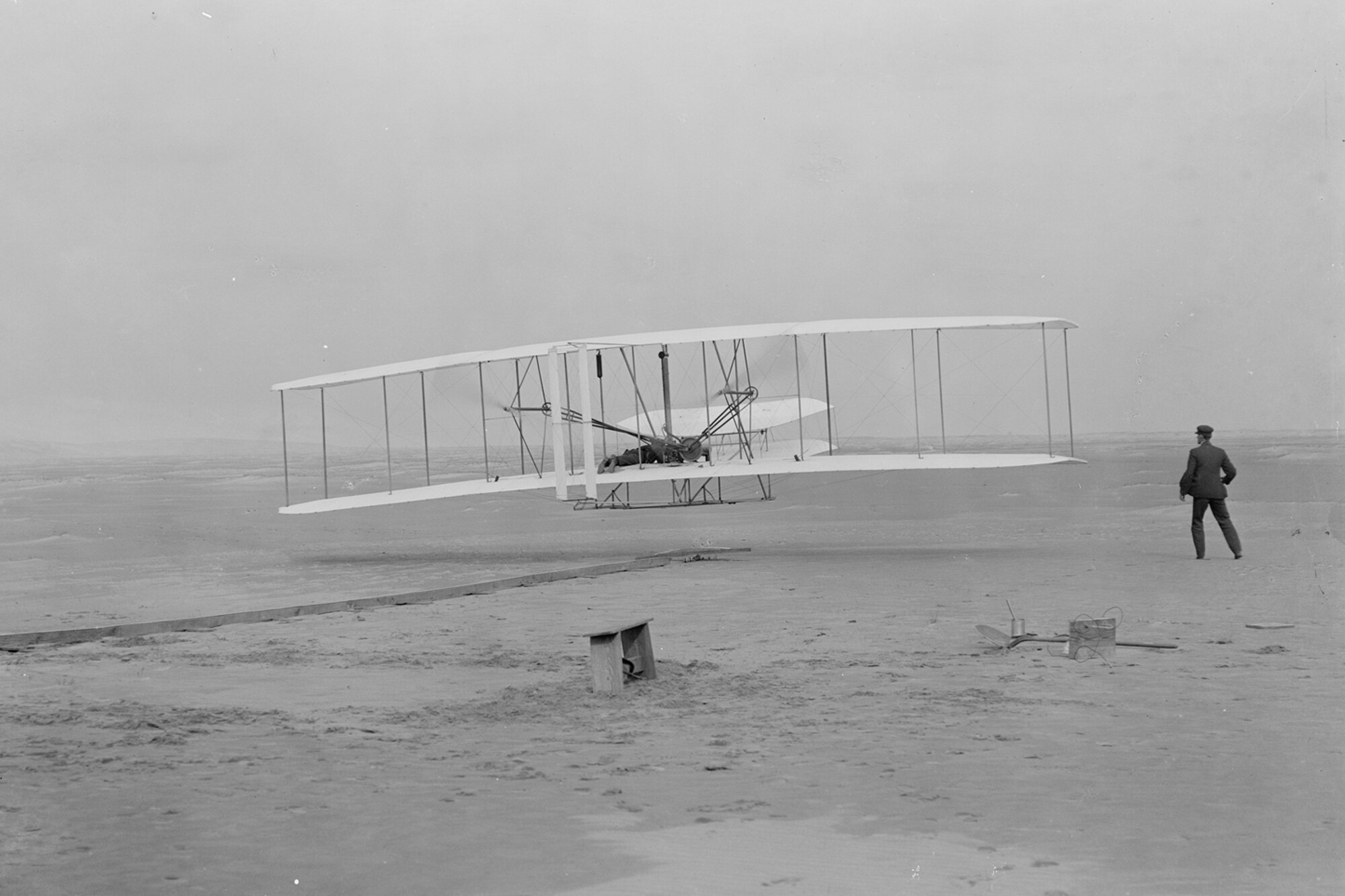 Orville Wright at the controls of the 1903 Wright Flyer during the first successful powered flight Dec. 17, 1903 at Kittyhawk, N.C., while Wilbur Wright looks on. The first flight at 10:35 a.m. was 120 feet and lasted 12 seconds. The 106th anniversary of the event will be celebrated Dec. 17, 2009 at the Wright Brothers Memorial, Wright-Patterson Air Force Base, Ohio. Today, visitors to Wright-Patt and the Dayton region can learn about the Wright Brothers at the Dayton Aviation Heritage National Historical Park.  (Library of Congress) 