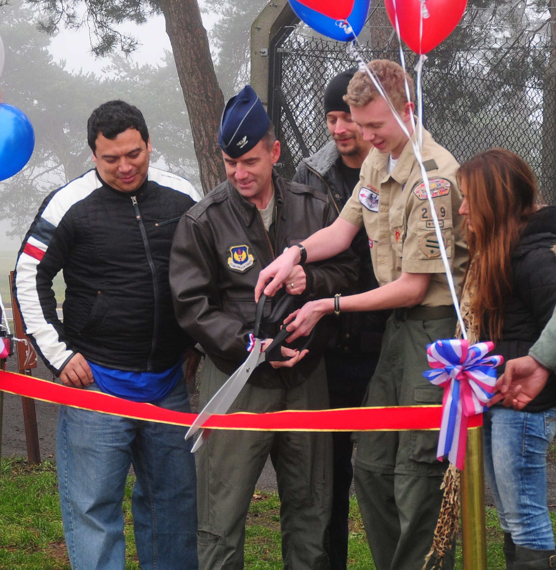 Joshua Kent, with the help of 48th Fighter Wing Commander Col. Jay Silveria, cut the ribbon during the ceremony to open brand new fitness stations at RAF Lakenheath, England, Dec. 11.  Entertainers Carlos Mencia (left) Kid Rock (middle) and Jessie James (right) were also in attendance.  Joshua Kent, a boy scout with Troop 219 here, initiated this project to earn his Eagle Scout badge.   The 15 new fitness stations can be found along the RAF Lakenheath running trail.  (U.S. Air Force photo by Staff Sgt. Connor Estes).    
