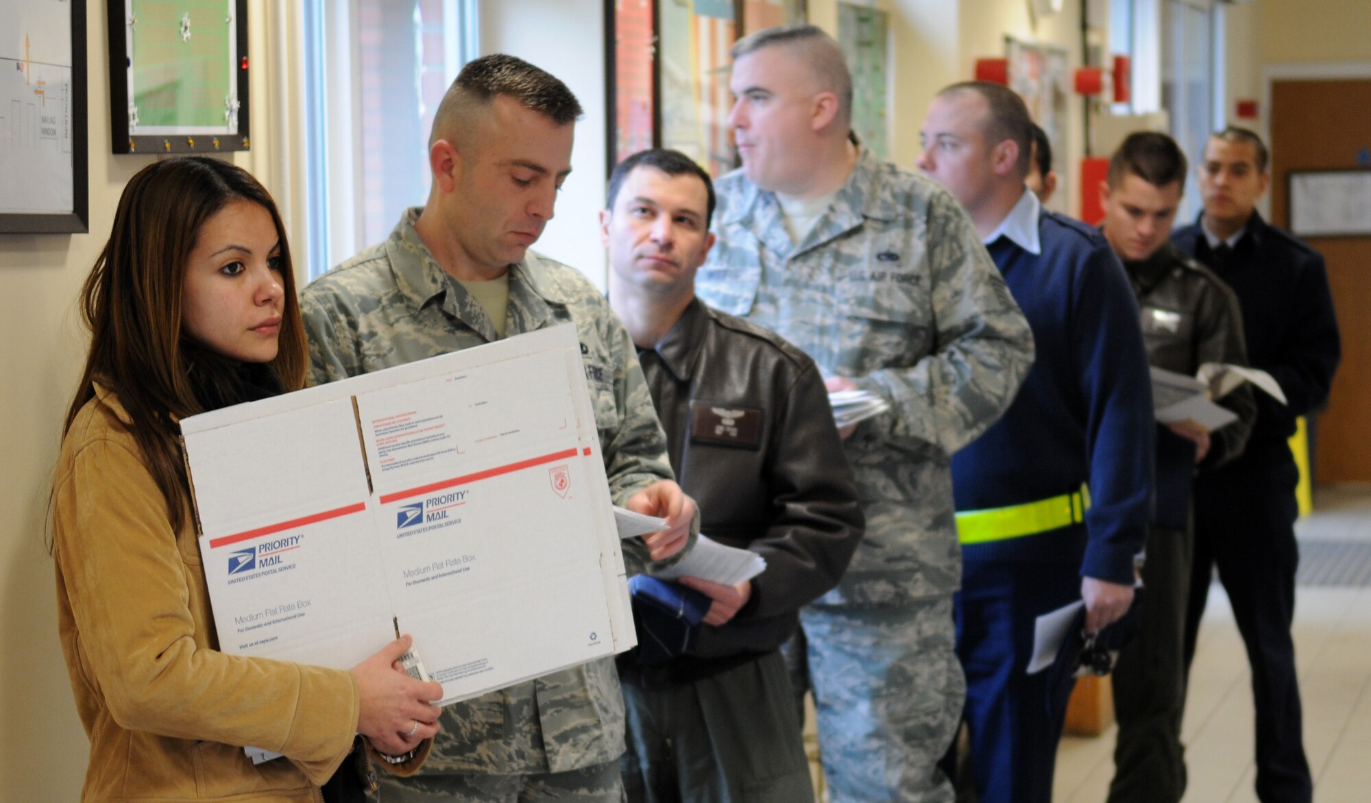 RAF MILDENHALL, England – Customers wait in line at the military post office pick-up window to retrieve packages Dec. 14. Customers can experience long lines and wait times during the afternoon rush which normally occurs from 11 a.m. to 1 p.m.  The post office has extended hours of operation with outgoing mail opening at 8:30 a.m. to 5 p.m. Monday through Friday and 9 a.m. to 1 p.m. Saturday. The pick-up window hours are 8 a.m. to 6 p.m Monday through Friday and 9 a.m to 1 p.m. Saturday. The post office will resume normal business hours Dec. 28. (U.S. Air Force photo/ Staff Sgt. Jerry Fleshman)