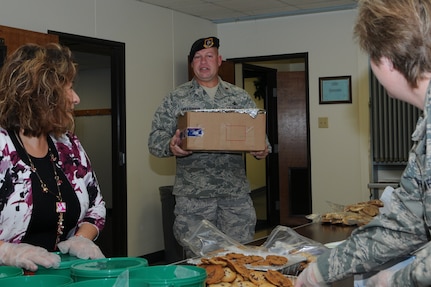 Maj. Frank Hellstern, 12th Security Forces Squadron commander, delivers Christmas cookies to  the Chapel Center Dec. 15 in support of the annual Cookie Crunch Drive, as Alice Rodriquez, Air Force Security Assitance Training Squadron (left) and Senior Master Sergeant Lisa Finuff, Air Force Personnel Center, package holiday treats for delivery. Last year the drive collected and distributed more than 8,000 cookies. This year's goal is set for 10,000 cookies.  (U S Air Force Photo/Don Lindsey)