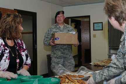 Maj. Frank Hellstern, 12th Security Forces Squadron commander, delivers Christmas cookies to  the Chapel Center Dec. 15 in support of the annual Cookie Crunch Drive, as Alice Rodriquez, Air Force Security Assitance Training Squadron (left) and Senior Master Sergeant Lisa Finuff, Air Force Personnel Center, package holiday treats for delivery. Last year the drive collected and distributed more than 8,000 cookies. This year's goal is set for 10,000 cookies.  (U S Air Force Photo/Don Lindsey)