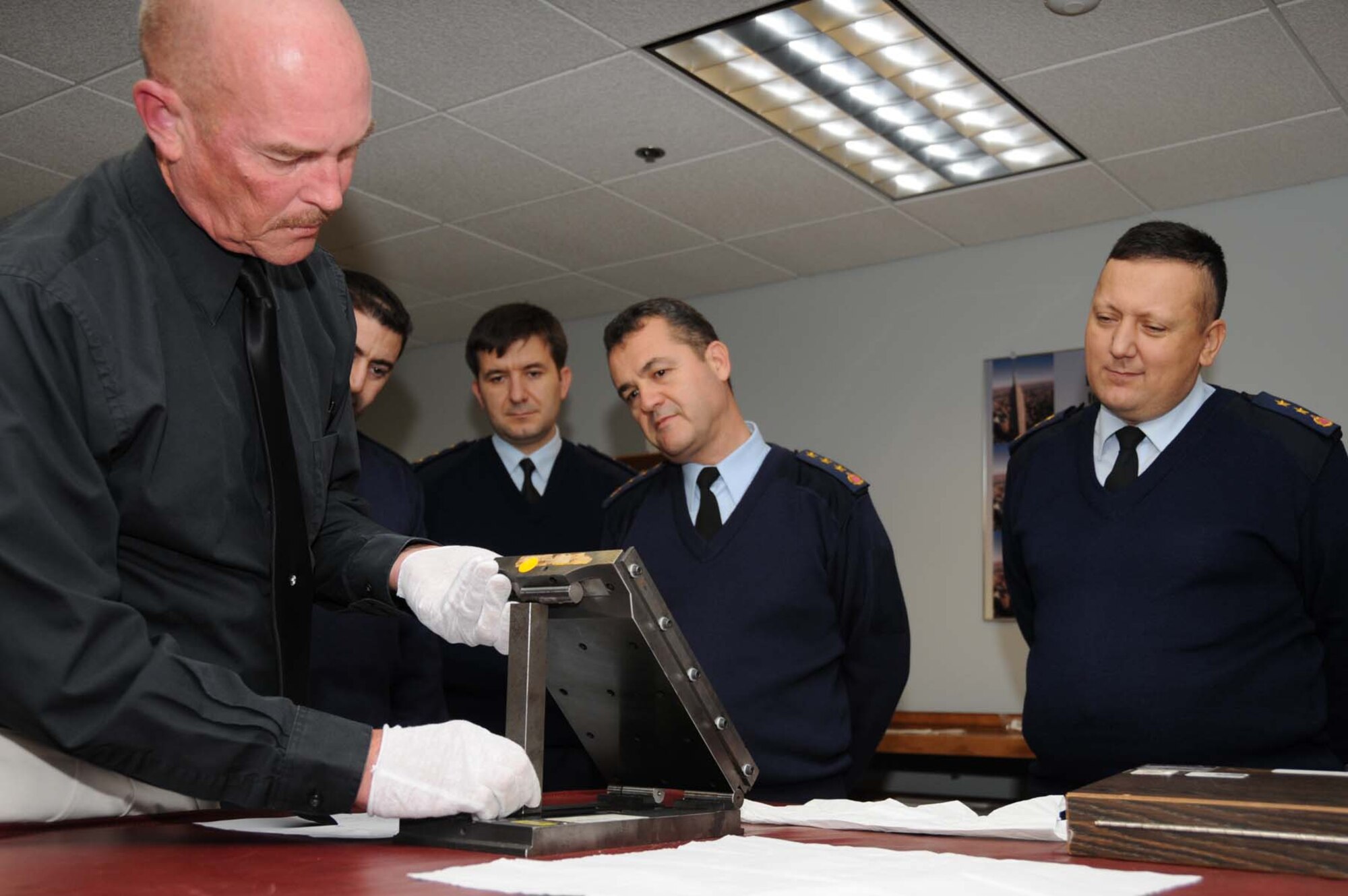 From left, Floyd Parsons, 332nd Training Squadron, shows Turkish Air Force officers Maj. Turan Sahin, Capt. Serkan Bahar, Col. Adnan Basturk and Lt. Col. Huseyin Bolat shows how a sine plate is used to generatre precision angles to calibrate angle measuring equipment at Wolfe Hall Dec. 8.  The officers toured 81st Training Group facilities last week as part of a Turkish Air Force education and training system improvement program.  (U.S. Air Force photo by Kemberly Groue)