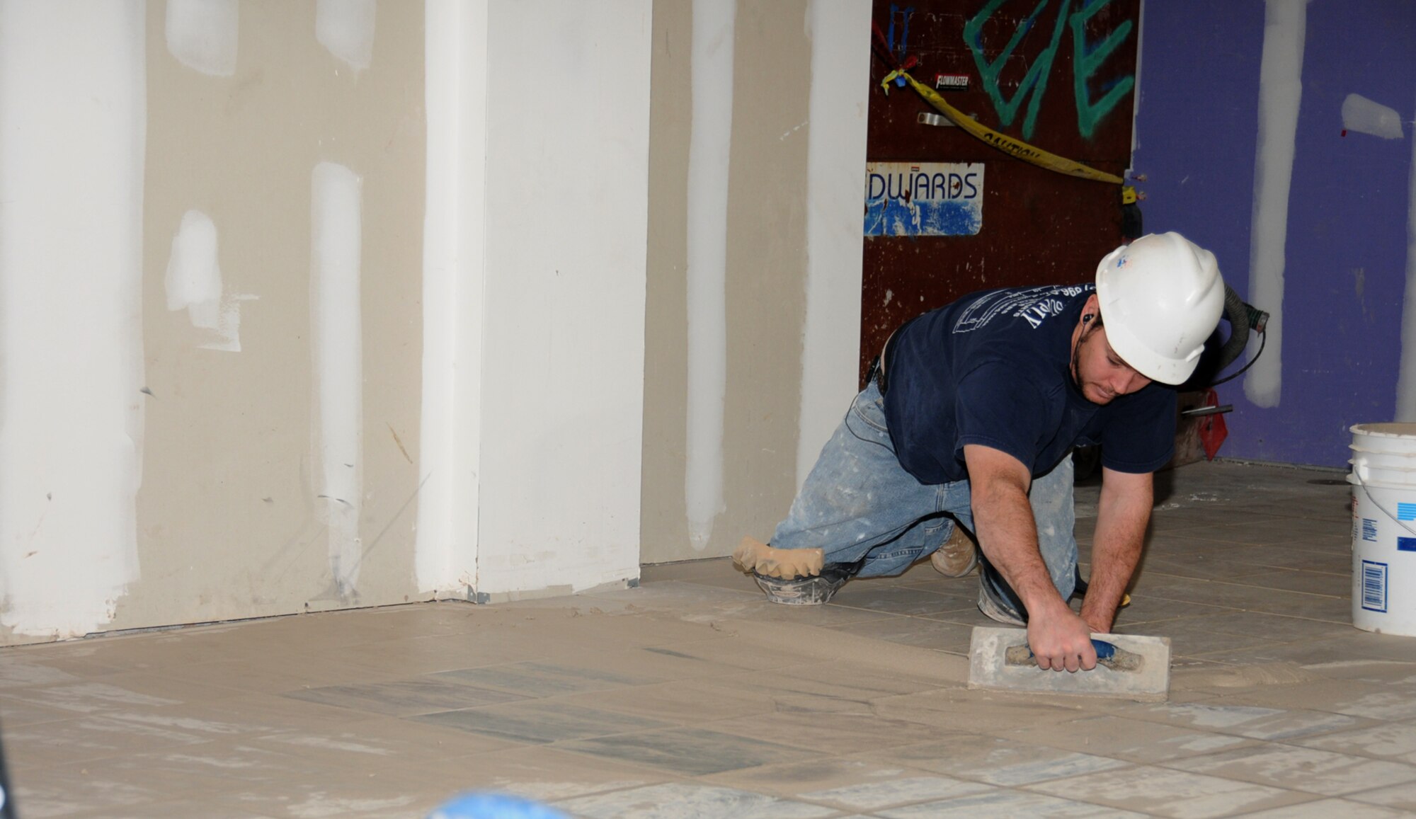 William Epperson from Sanders Hyland Flooring lays tile in the foyer.   (U.S. Air Force photo by Kemberly Groue)