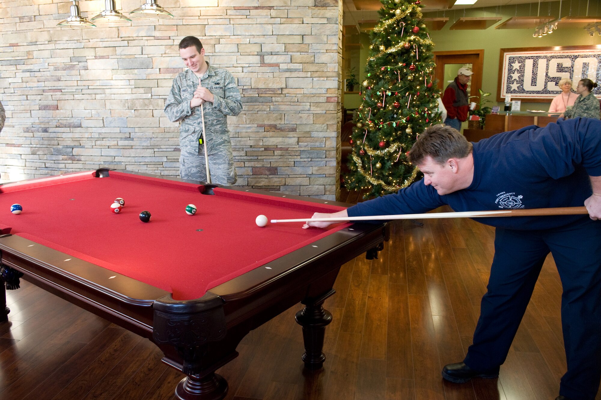Senior Airman Nicolas Lander, 436th Aerial Port Squadron, and Steve Kerr, 436th Civil Engineering Squadron, relax with a quick game of pool Dec. 11 at the United Service Organization lounge. The fire protection flight of the 436th CES have volunteered their time to keep the USO lounge open 24 hours on Fridays. (U.S. Air Force photo/Brianne Zimny)
