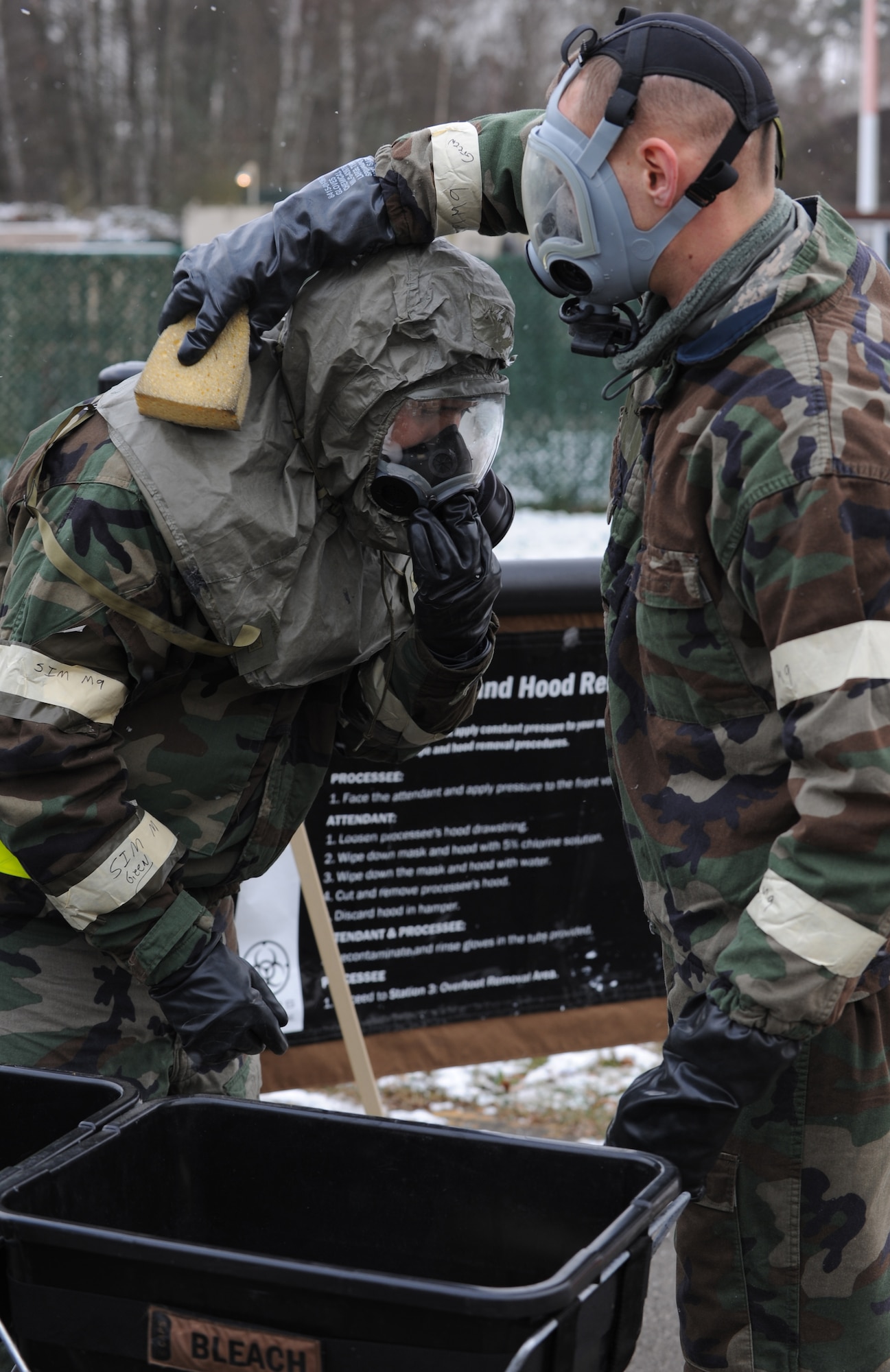 U.S. Air Force Staff Sgt. Jonathan Jones and Senior Airman Joel Halpin, 86th Maintenance Squadron, utilize the buddy system to decontaminate each other during an exercise scenario, Ramstein Air Base, Germany, Dec. 15, 2009. The wing is conducting an exercise to evaluate its mission readiness and the ability to survive and operate in a chemical environment. (U.S. Air Force photo by Airman 1st Class Caleb Pierce)