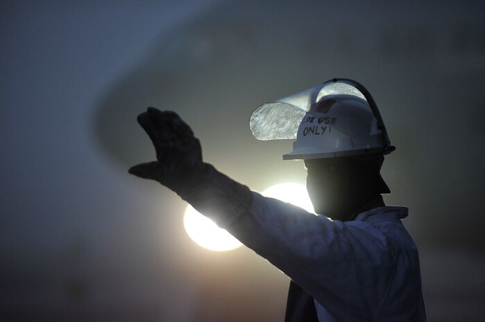 U.S. Air Force Staff Sgt. Rushad Stroman uses hand gestures to communicate with another Airman to find out if sufficient amounts of liquid oxygen have been loaded onto a C-17 at Charleston Air Force Base, S.C., Dec. 14, 2009. The 437th Aircraft Maintenance Squadron at Charleston AFB primarily performs flightline tasks to include daily mission launch and recovery, pre- and post-flight inspections, maintenance troubleshooting, aircraft systems repair and modifications. Sergeant Stroman is an aircraft electrical environmental technician with the 437 AMXS. (U.S. Air Force photo by James M. Bowman)(RELEASED)