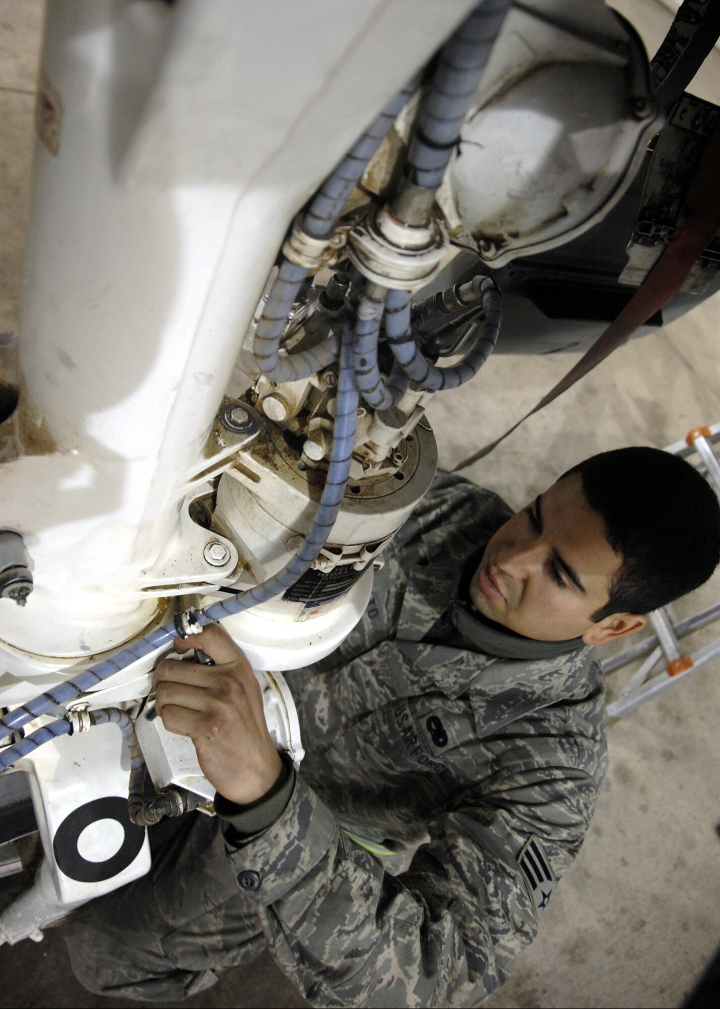 KANDAHAR AIRFIELD, Afghanistan -- Senior Airman Julio Morato, 451st Expeditionary Maintenance Squadron Maintenance Flight crew chief, adjusts the taxi light wire harness attached to the nose wheel steering unit cover here, Dec. 10, 2009. Airman Morato is deployed from Davis-Monthan Air Force Base, Ariz.  (U.S. Air Force photo/senior Airman Timothy Taylor)