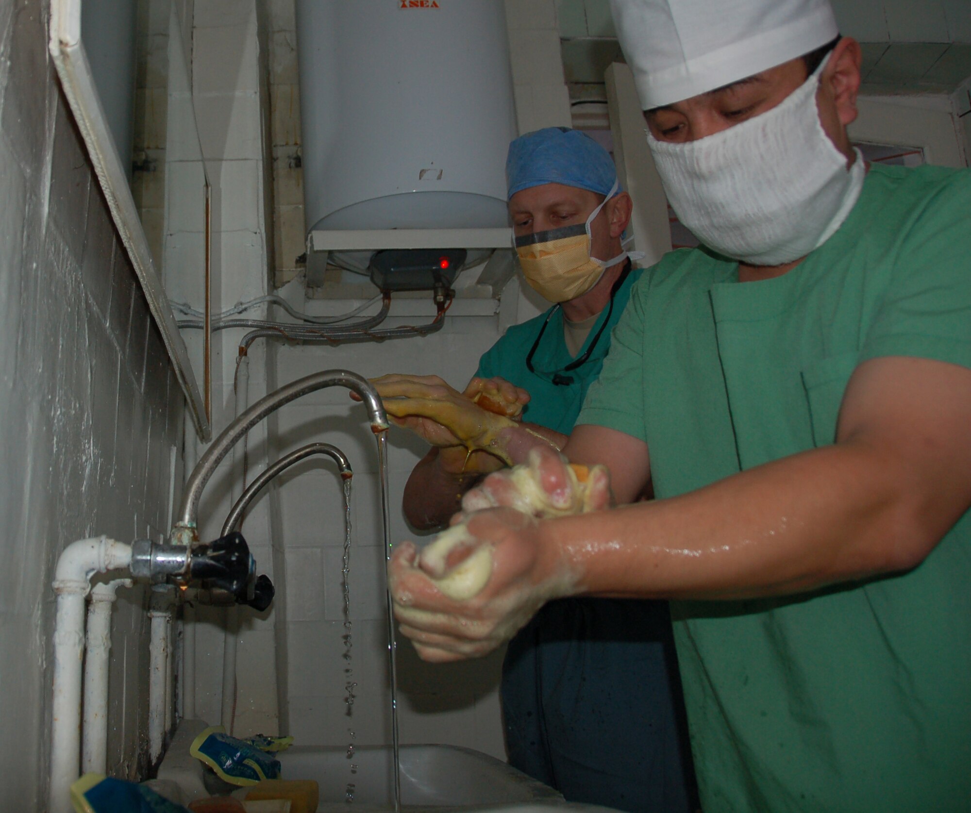 TRANSIT CENTER AT MANAS, Kyrgyzstan -- (Far left) Lt. Col. Joseph Browne cleans up for a surgery alongside a Kyrgyz surgeon before a joint medical operation in a military hospital in Kyrgyzstan Dec. 11, 2009. During their operation, Colonel Browne and the Kyrgyz doctor operated on a patient with broken collar bones. During the visit, the team of Airmen from the Transit Center assisted their  Kyrgyz counterparts with two surgical procedures.  The team of Airmen was led by Colonel Flyer, 376th Expeditionary Medical Group commander. (U.S. Air Force photo/Staff Sgt. Olufemi Owolabi)