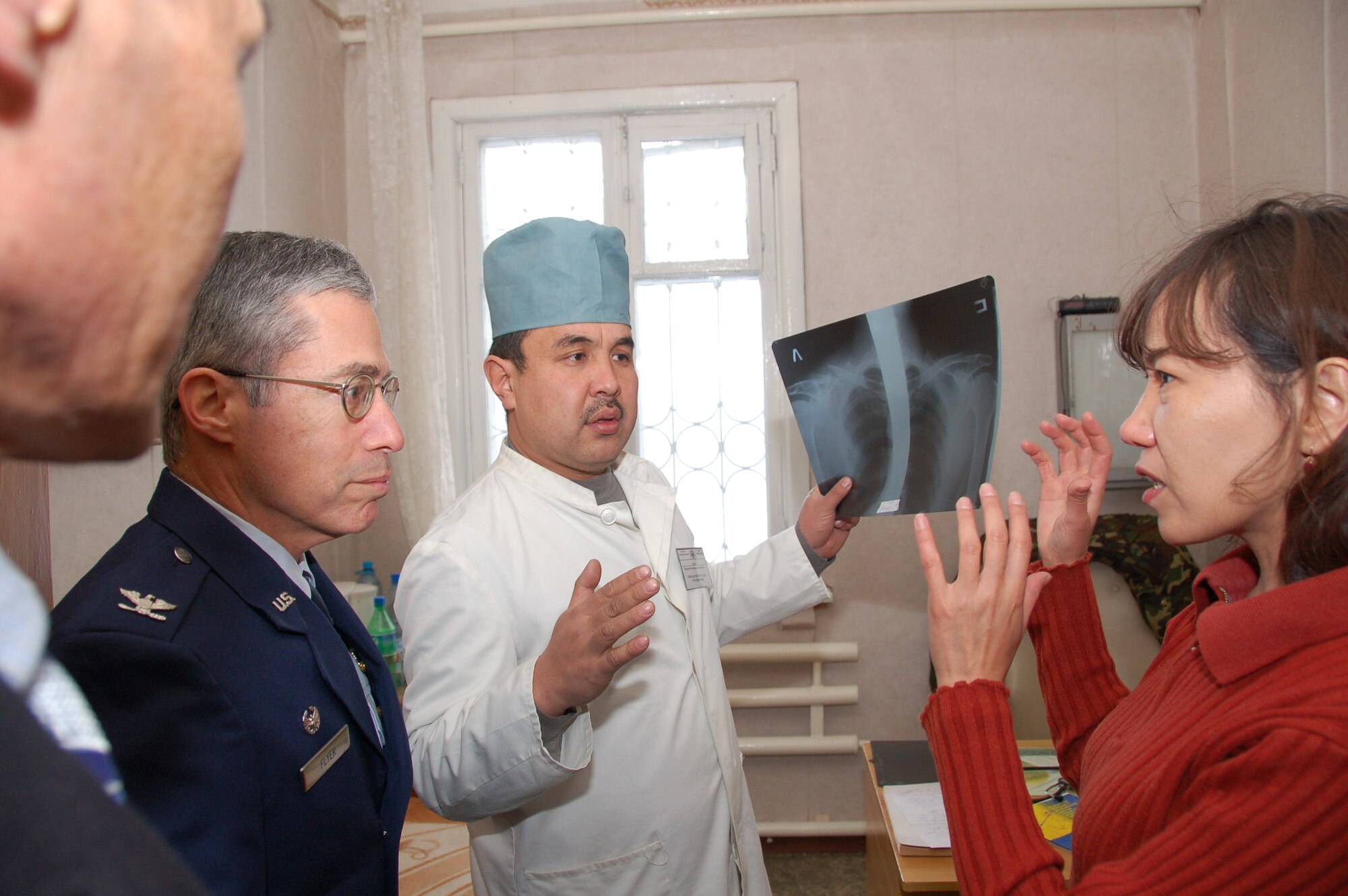 TRANSIT CENTER AT MANAS, Kyrgyzstan - Col. Jerrold Flyer, 376th Expeditionary Medical Group commander, listens as Janyl Sabirova, translator, explains the type injury the colonel will be operating on during a joint surgery between him and a Kyrgyz doctor at a Kyrgyz hospital, Dec. 11,2009. A team of Airmen from the Transit Center visited the hospital and assisted the Kyrgyz in two separate surgical operations. The joint procedures were part of an ongoing partnership between medical Airmen at the Transit Center and their counterparts at the Besh-Kungei Military Hospital. (U.S. Air Force photo/Staff Sgt. Olufemi Owolabi)