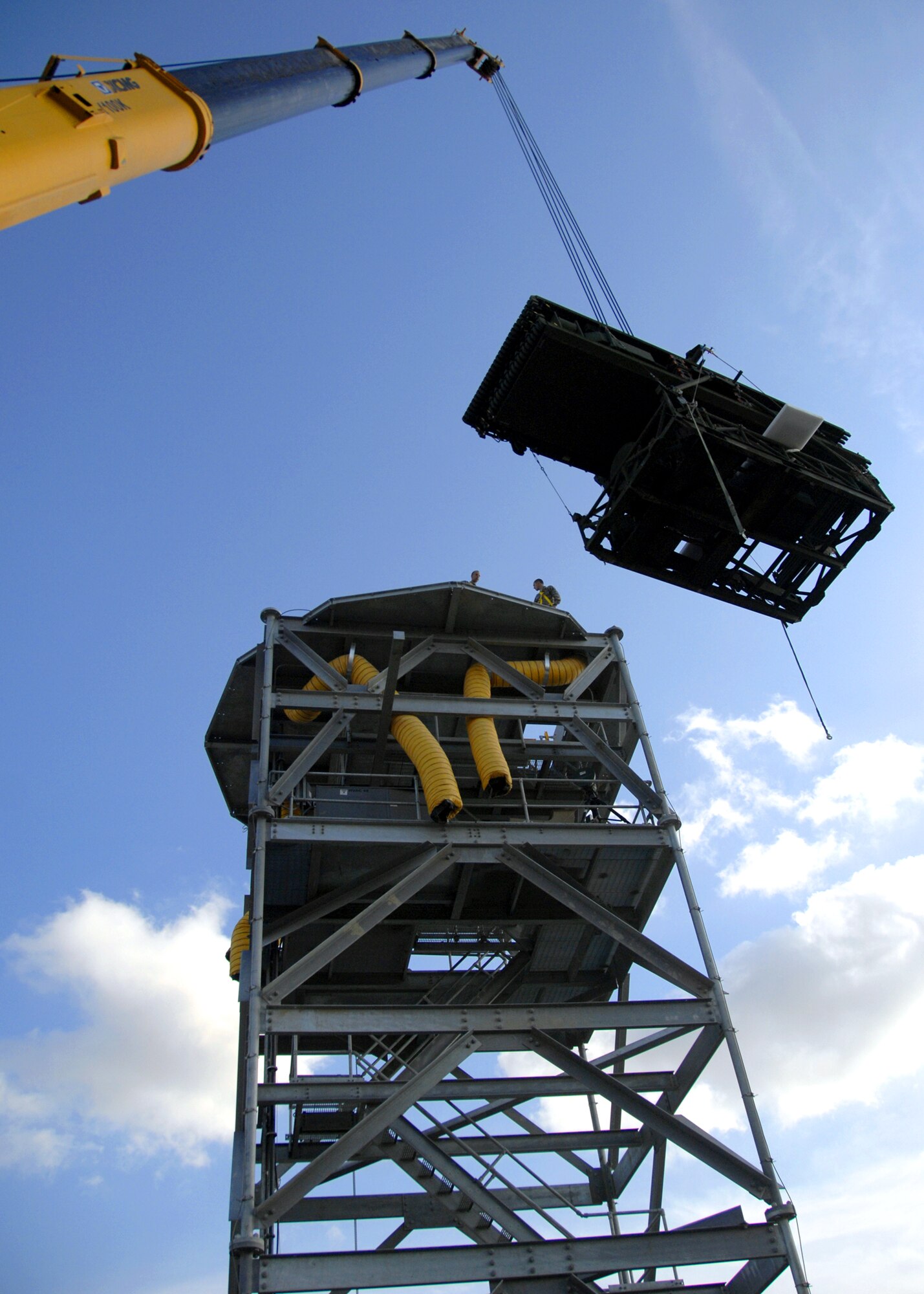 Airmen from the 73rd Expeditionary Air Control Squadron spot a crane as one
of two new “radomes” is installed here, Dec. 9, 2009. The installation of the radomes will greatly reduce the effects and costly damage caused by the harsh local climate on the An/TPS-75 radar towers, which were used for the past two decades.  The amount of maintenance required for cleaning and repair will be greatly reduced when this project is completed, increasing the operational reliability for members of the 73rd EACS.  (U.S. Air Force photo/Senior Airman Timothy Taylor)