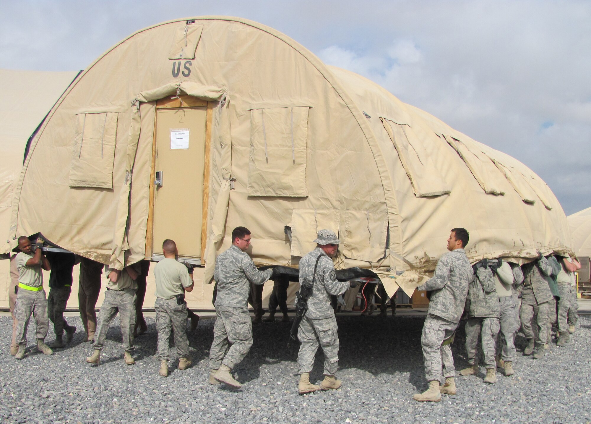 Airmen from all three groups within the 451st Air Expeditionary Wing worked together to move an Alaskan shelter here Dec. 10. The tent was moved to make room for a brand new Clam Shell Hangar that was being installed by a J2 Team.  It took approximately 30 Airmen from the 451st Expeditionary Operations Group, Maintenance Group and Mission Support Group to lift the Alaskan shelter and place it on the newly constructed foundation on Golf Ramp. (U.S. Air Force photo/Senior Master Sgt. Anthony Morikawa) 