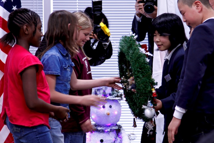 Students of Matthew C. Perry Elementary School here present a Christmas wreath to students of Kawashimo Elementary School at the Iwakuni City Town Hall building Dec. 15. The wreath exchange was part of a U.S.-Japan Friendship Exchange sponsored by the Chugoku-Shikoku Defense Bureau in conjunction with Iwakuni City, the Municipal Board of Education and the station.