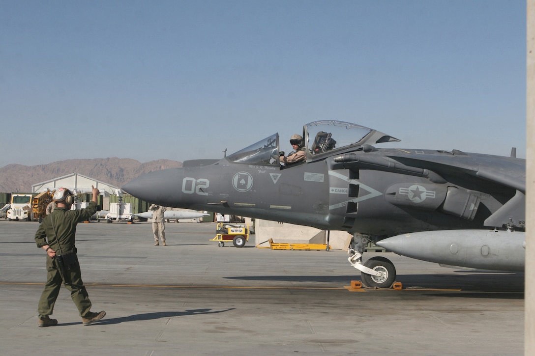A plane captain with Marine Attack Squadron 231, Marine Aircraft Group 40, Marine Expeditionary Brigade-Afghanistan, taxis the Harrier for Lt. Col. David Forrest, VMA-231's commanding officer and AV-8B Harrier pilot, following a flight here Dec. 16. (U.S. Marine Corps photo by Lance Cpl. Samuel A. Nasso)