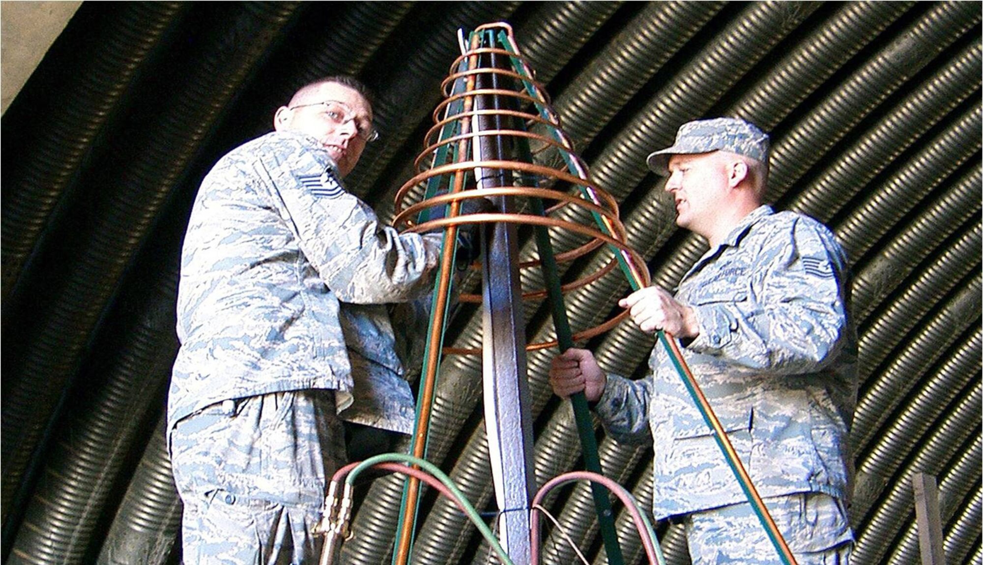 KIRKUK REGIONAL AIR BASE, Iraq ?Tech. Sgts. Ryan Stephens (left), and Jacob Erickson, heating, ventilation and air conditioning technicians assigned to the 506th Expeditionary Civil Engineer Squadron, mold the coils for a 12-foot Christmas tree Dec. 3.  The 506th ECES designed and fabricated the tree in preparation for the 6,500 Coalition Forces who will be deployed here during the holiday season. Sergeant Stephens, a native of Vancouver, Wash., and Sergeant Erickson, a native of Saint Helens, Ore., are Reservists deployed from the 446th Civil Engineer Squadron, McCord Air Force Base, Wash.  (Courtesy photo)