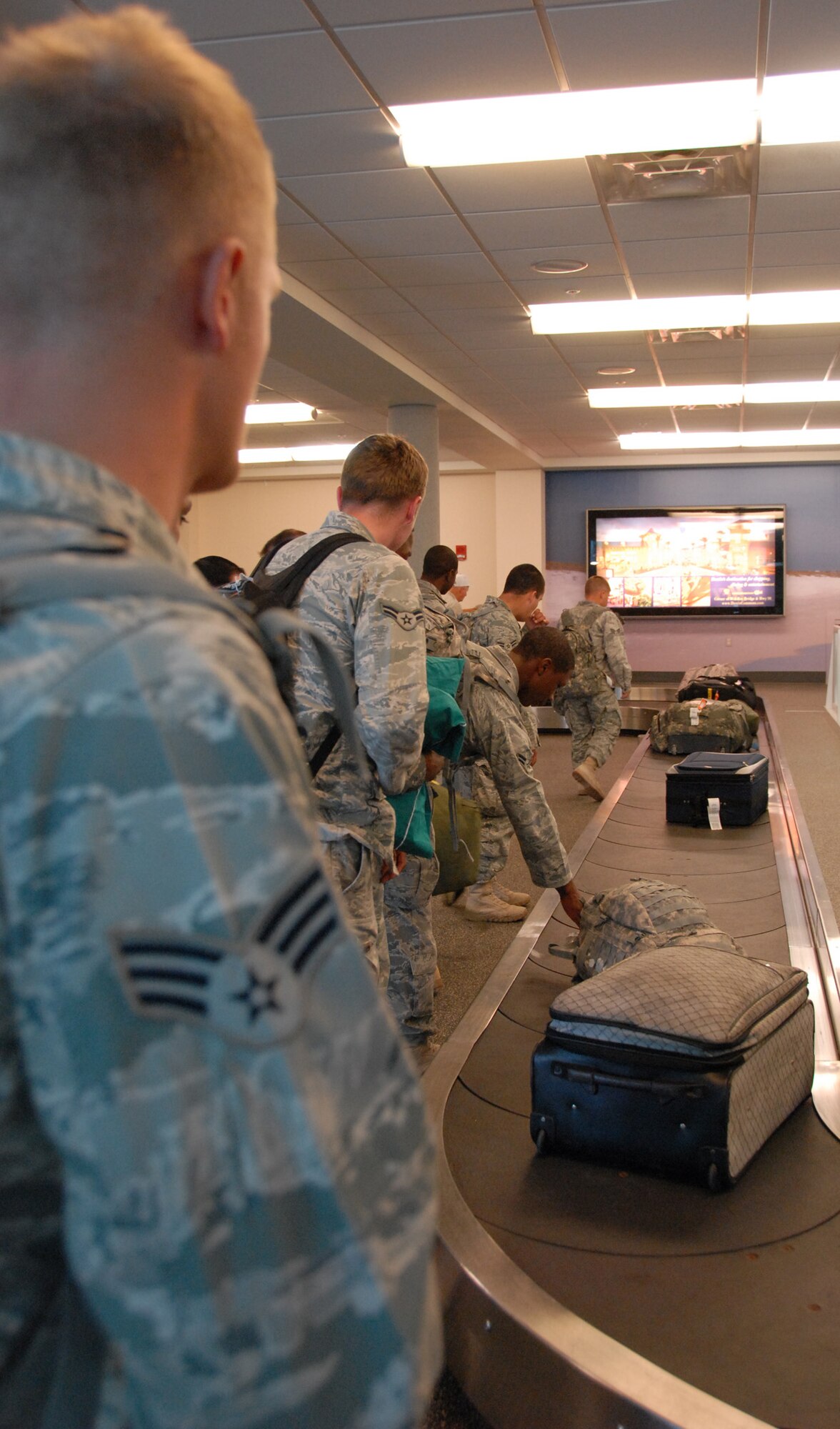 A senior airman waits for his luggage, while other defenders pull off their bags upon returning from a deployment to Southwest Asia Dec. 16.  Approximately 20 Security Forces Airmen returned.  Security forces is one of the highest deployment-tasked career fields in the Air Force.  (Air Force photo/ Samuel King Jr.)