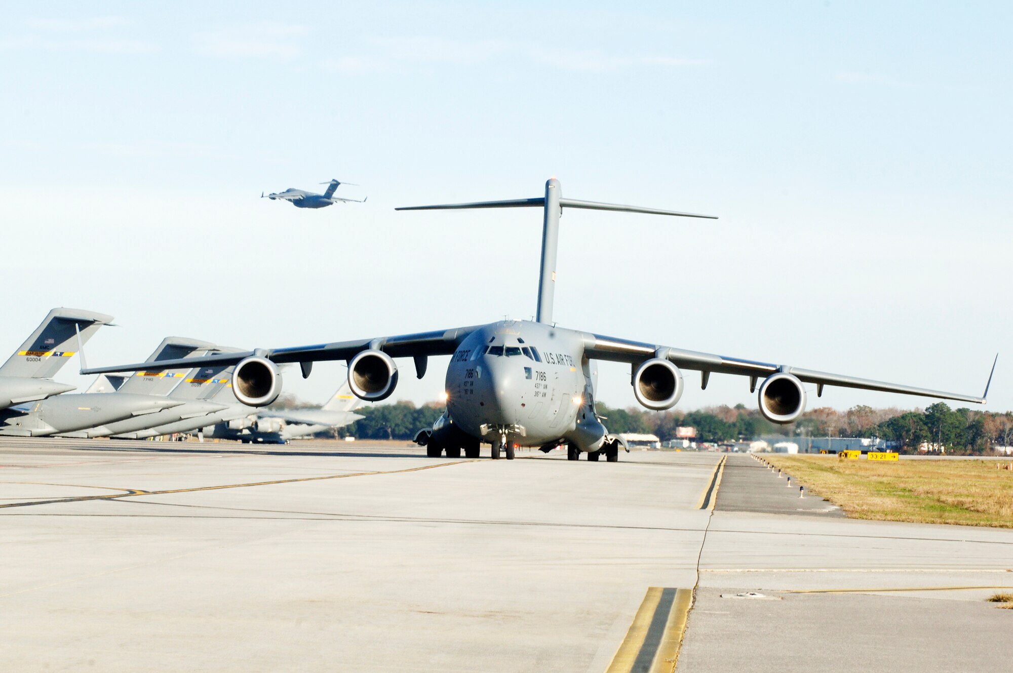 A C-17 Globemaster III from Charleston Air Force Base, S.C., takes off as another C-17 taxis in preparation for a strategic brigade airdrop exercise over North Auxiliary Airfield Dec. 16, 2009, near North, S.C., demonstrating the global projection of U.S. airpower. Charleston AFB Airmen conducted a large formation exercise utilizing 10 C-17 aircraft. Soldiers from the 2-319th Airborne Field Artillery, 82nd Airborne Division at Ft. Bragg, N.C., were airdropped along with cargo pallets to simulate the seizure of a remote airfield. (U.S. Air Force photo/Staff Sgt. Marie Brown)