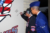 Retired Capt. Claude R. Platte, a former Tuskegee Airman, signs a wall at the 323rd Training Squadron dedicated to the Tuskegee Airmen as his great nephew Airman Christopher Platte, 331st Training Squadron, looks on. Capt. Platte was the first African-American officer to be trained and commissioned in the Air Force pilot training program. (U.S. Air Force photo/Alan Boedeker)