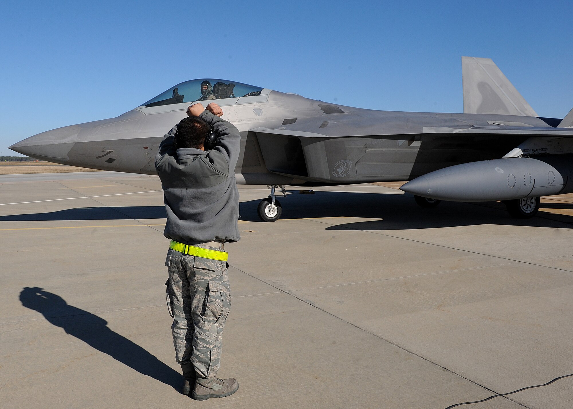LANGLEY AIR FORCE BASE, Va. -- Airman 1st Class Jacob Lerma, 27th Aircraft Maintenance Squadron crew chief, marshals in Capt. Matthew Howard, 27th Fighter Squadron pilot, after his return from a deployment Dec. 16. The 27th FS deployed six F-22 Raptors in support of a 40 day training exercise in Southwest Asia. (U.S. Air Force photo/Airman Rebecca Montez) 