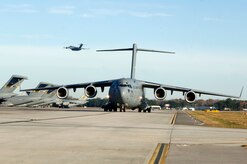 A C-17 aircraft from Charleston AFB takes off as another C-17 taxi's in preparation for a strategic brigade airdrop exercise over North Auxiliary Airfield near North, S.C., Dec. 16 demonstrating the global projection of U.S. airpower. Charleston AFB conducted a large formation exercise utilizing 10 C-17 aircraft. Soldiers from the 2-319th Airborne Field Artillery, 82nd Airborne Division, Ft. Bragg, N.C., were airdropped along with cargo pallets to simulate the seizure of a remote airfield. (U.S. Air Force photo/Staff Sgt. Marie Brown)(RELEASED)