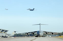 Two C-17 aircraft from Charleston AFB take off as another C-17 taxi's in preparation for a strategic brigade airdrop exercise over North Auxiliary Airfield near North, S.C., Dec. 16, 2009, demonstrating the global projection of U.S. airpower. Airborne Soldiers from the 2-319th Airborne Field Artillery, 82nd Airborne Division, Ft. Bragg, N.C., were airdropped in the exercise along with cargo pallets to simulate the seizure of a remote airfield, providing a joint training opportunity for the Airmen and Soldiers. The training mission included airdrops over North Auxiliary Airfield, aerial refueling training and simulated aeromedical evacuation. (U.S. Air Force photo/Staff Sgt. Marie Brown)(RELEASED) 

