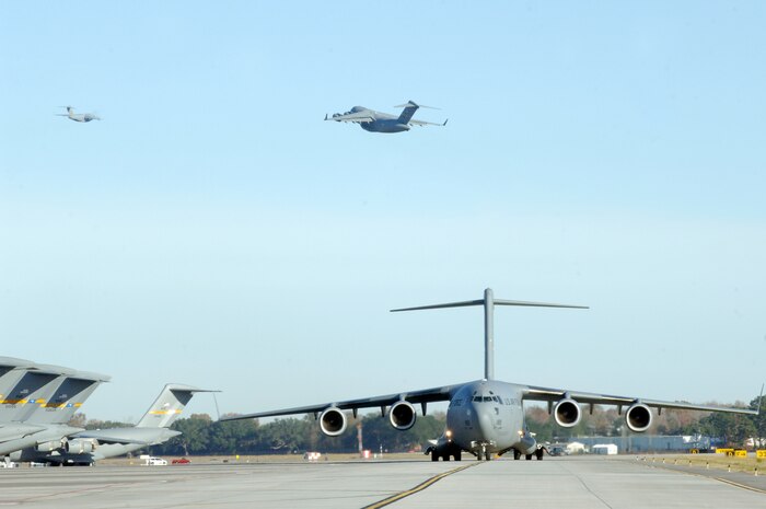 A C-17 aircraft from Charleston AFB takes off as another C-17 taxi's in preparation for a strategic brigade airdrop exercise over North Auxiliary Airfield near North, S.C., Dec. 16, 2009, demonstrating the global projection of U.S. airpower. Airborne Soldiers from the 2-319th Airborne Field Artillery, 82nd Airborne Division, Ft. Bragg, N.C., were airdropped in the exercise along with cargo pallets to simulate the seizure of a remote airfield, providing a joint training opportunity for the Airmen and Soldiers. The training mission included airdrops over North Auxiliary Airfield, aerial refueling training and simulated aeromedical evacuation. (U.S. Air Force photo/Staff Sgt. Marie Brown)(RELEASED)