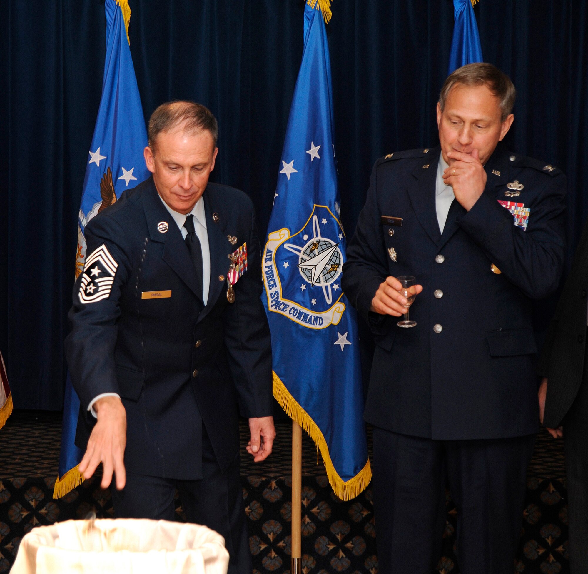 Chief Master Sgt. Timothy Omdal, former 21st Space Wing command chief, and retired Col. Mathew Toth toast the retirement of Chief Omdal’s security forces badge Dec. 11 at the Peterson Club. Chief Omdal served the majority of his 29-year career as a security forces Airman and, keeping with tradition, charged, toasted, and broke a glass in honor of retiring his badge. (Air Force photo by Craig Denton)
