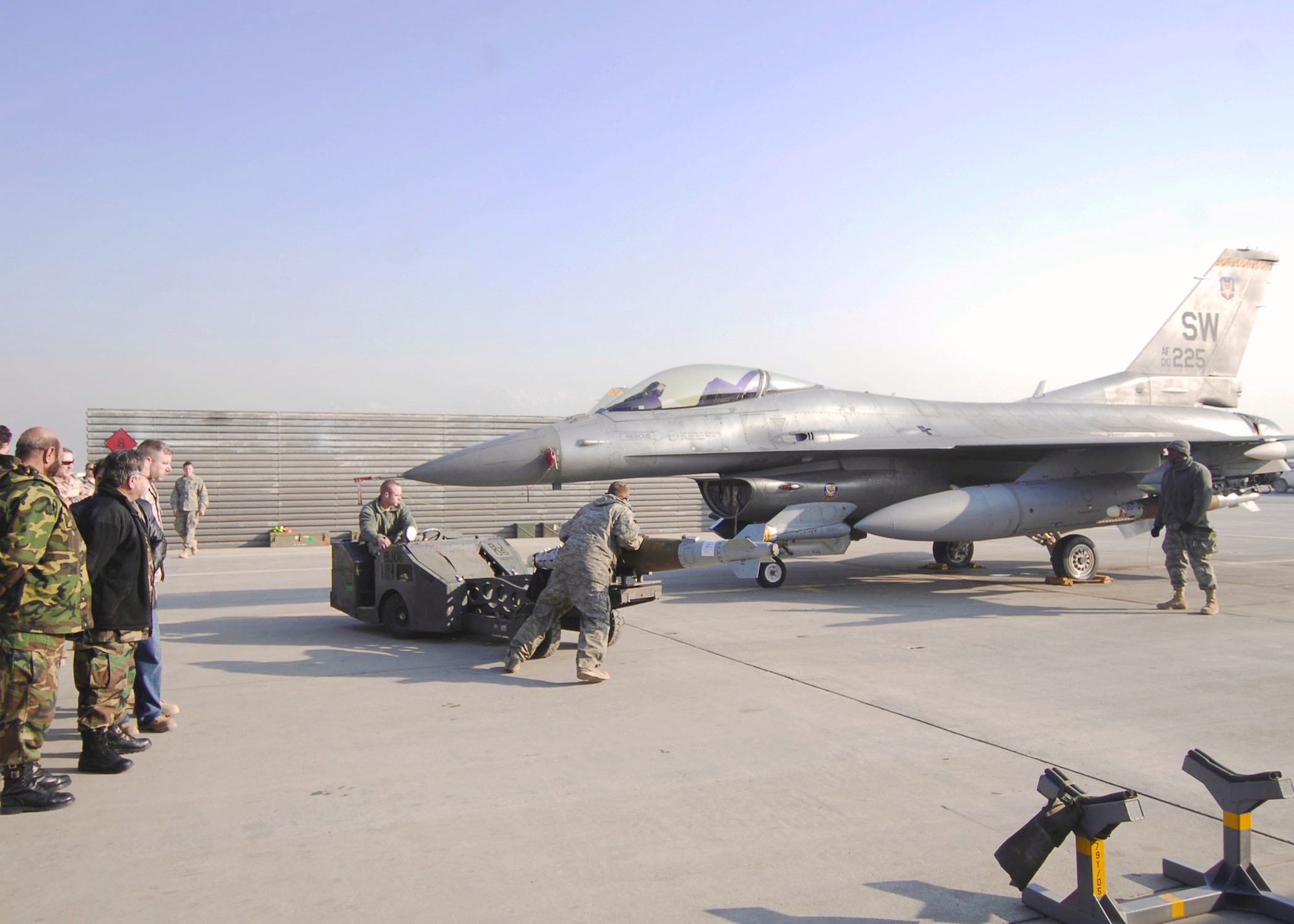 Staff Sgt. Sam Arpy drives a bomb-lift truck while Airman 1st Class John Ackerman assists him to the bomb rack of an F-16 Fighting Falcon Dec. 19, 2009, at Bagram Airfield, Aghanistan. Airman 1st Class Carl Jones (far right) spots Sergeant Arpy. All weapons load crew Airmen are deployed from Shaw Air Force Base, S.C. and were demonstrating proper loading procedures for Afghan National Army Air Corps Brig. Gen. Abdul Wahab Wardak and other officials, Dec. 19, 2009. (U.S. Air Force photo/Capt. David Faggard)