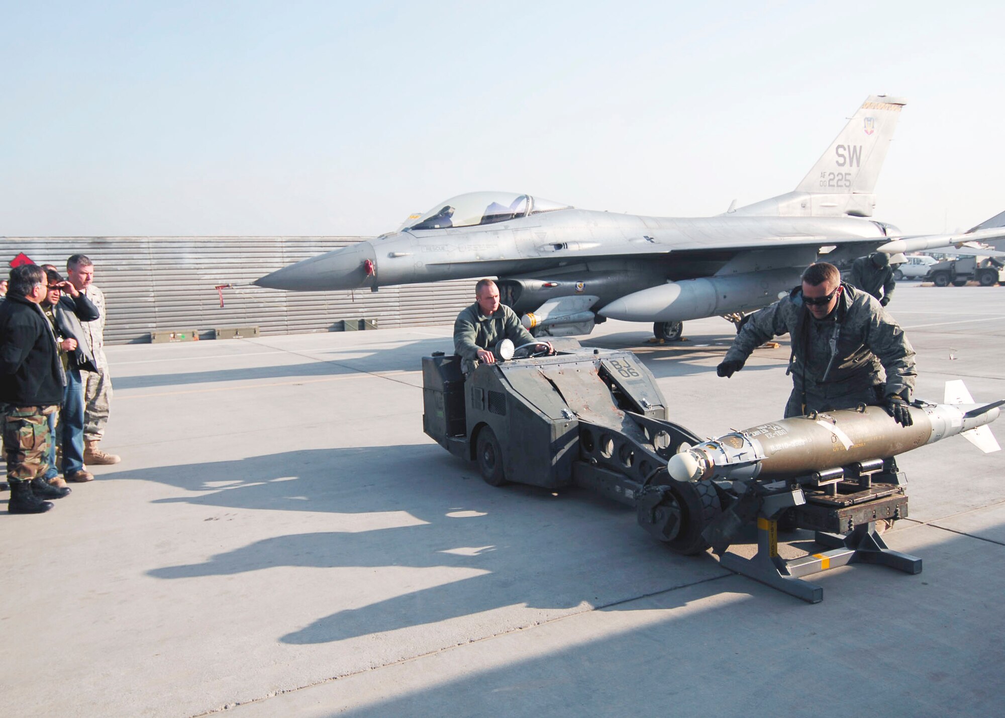 Staff Sgt. Sam Arpy prepares to lift a Joint Direct Attack Munition with a bomb-lift truck while Airman 1st Class John Ackerman prepares to tie down the bomb to the lift Dec. 19, 2009, at Bagram Airfield, Aghanistan. Both weapons load crew Airmen are demonstrating proper loading procedures for Afghan National Army Air Corps Brig. Gen. Abdul Wahab Wardak and other officials. (U.S. Air Force photo/Capt. David Faggard)