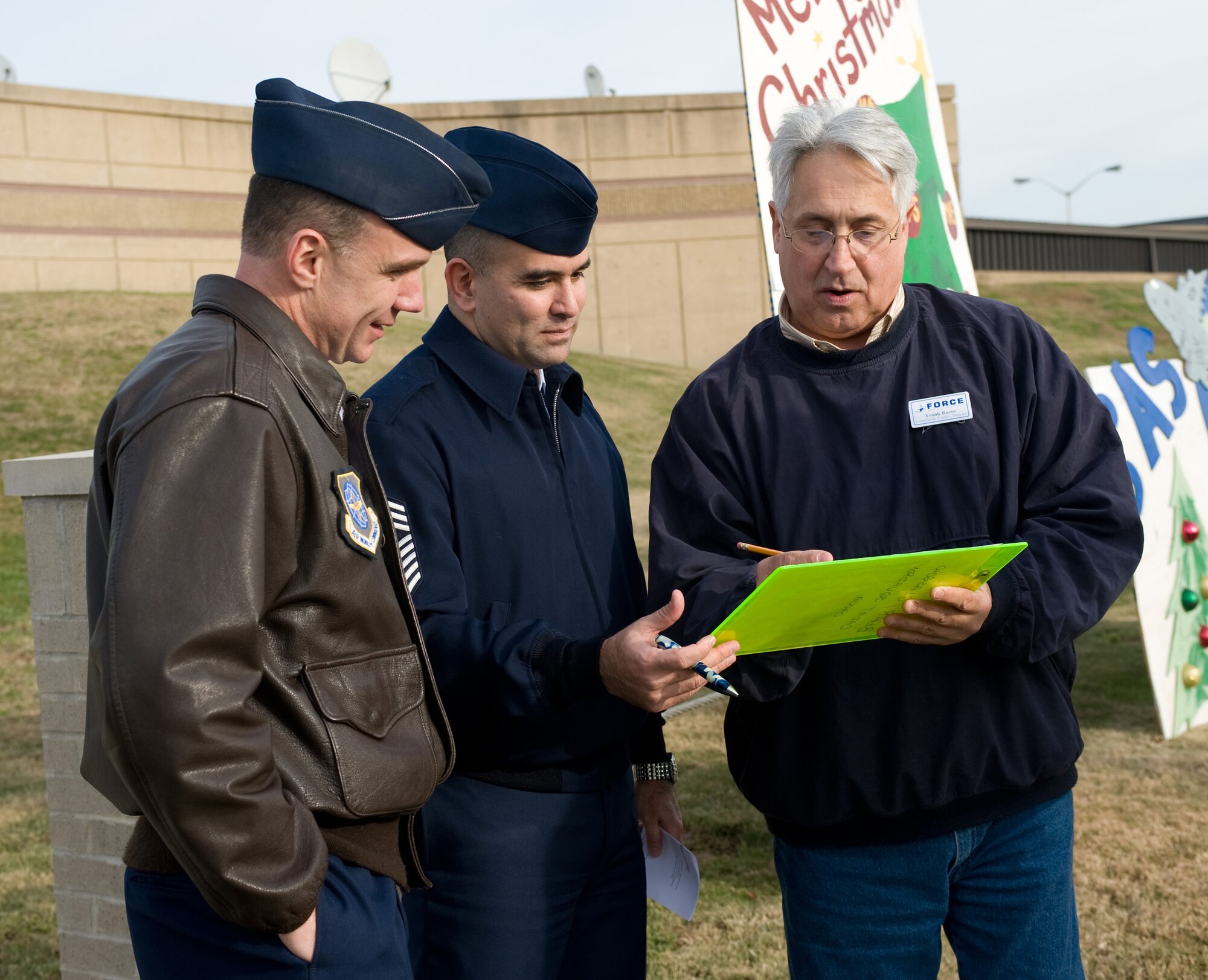 (From right) Frank Russo, 436th Force Support Squadron Community Activity Center director, briefs Chief Master Sgt. John Evalle, 436th Airlift Wing command chief, and Col. Manson Morris, 436th AW commander, about the rules for the Holiday Card Lane judging Dec. 14. Holiday Card Lane is an annual competition for squadrons to decorate a 4 foot by 8 foot plywood card for the holiday season. (U.S. Air Force photo/Brianne Zimny)