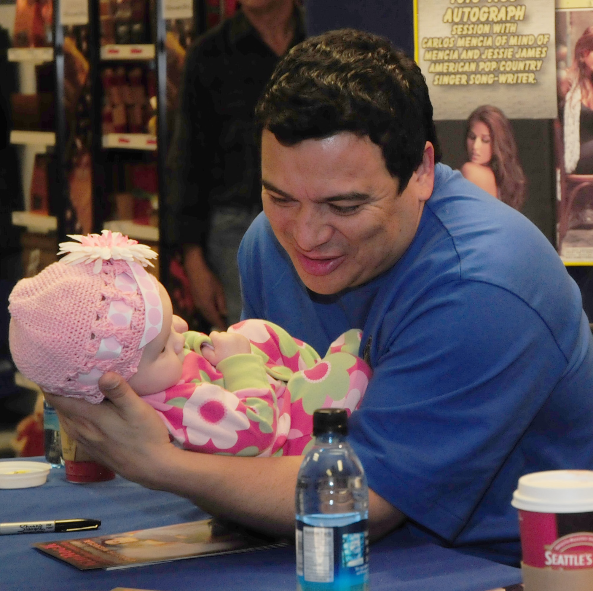 Comedian Carlos Mencia takes a break from signing autographs at the RAF Lakenheath Base Exchange to hold Carys Wigginton, 5 months, daughter of Tech. Sgt. Michael Wigginton, 48th Component Maintenance Squadron, at RAF Lakenheath, England, Dec. 11.  Mr. Mencia entertained military families in Hangar 7 at RAF Lakenheath, England during the Tour for the Troops 2009 concert.  The comedian was joined by singers Kid Rock and Jessie James as they toured various bases in Europe and Southwest Asia to show their support and appreciation for the military.  (U.S. Air Force photo by Staff Sgt. Connor Estes)