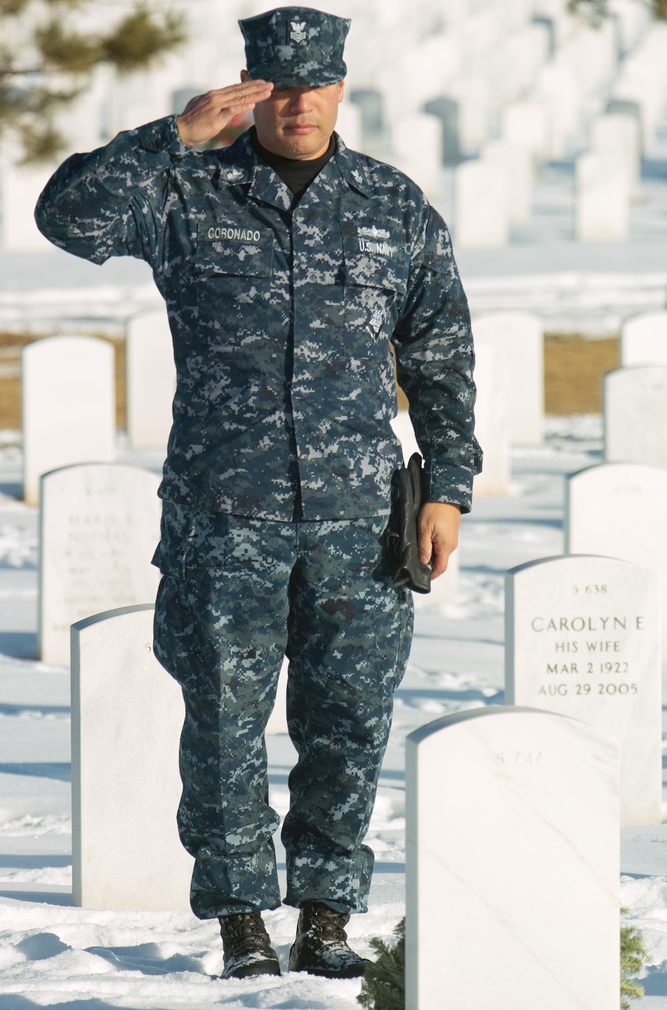Petty Officer First Class Manuel Coronado, Navy Information Operations Command Colorado, salutes after placing a wreath on a veteran's grave Dec. 12. (U.S. Air Force photo by Master Sgt. Steven Clark)