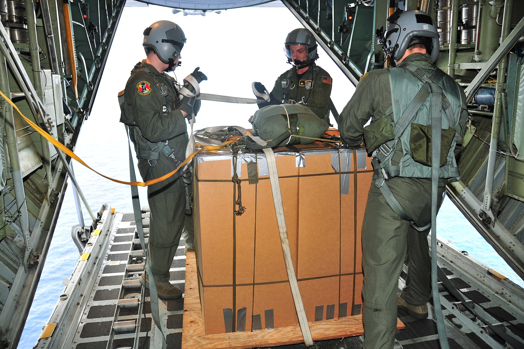 CHUUK, Commonwealth of the Northern Marianas Islands --  (Left to right) Airman 1st Class Jason Barbieri, Senior Airman Dustin DeVeaux, and Lt. Col. David Kincaid, all from the 36th Airlift Squadron, remove cargo straps from the first bundle of donated goods during Operation Christmas Drop Dec. 16. Operation Christmas Drop, the longest running humanitarian airlift mission in the world, delivers supplies to remote islands of the Commonwealth of the Northern Marianas Islands of Yap, Palau, Chuuk and Pohnpei. (U.S. Air Force photo/Tech. Sgt. Kimberly Spinner)