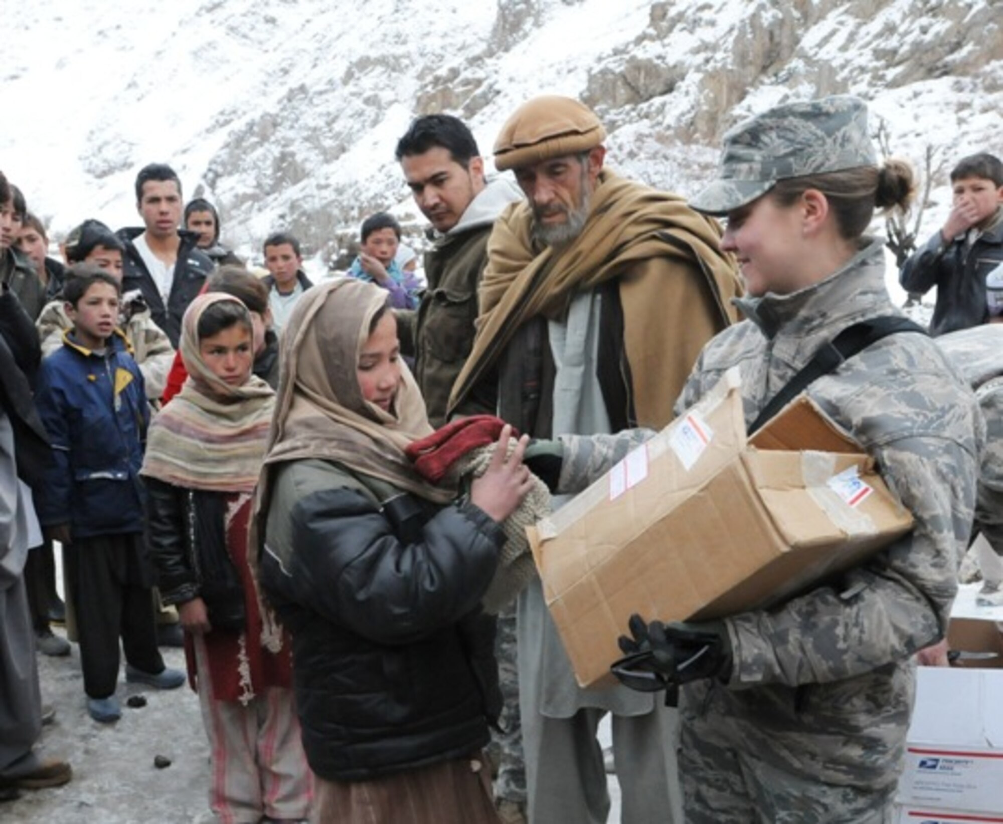 PANJSHIR PROVINCE, Afghanistan – Panjshir Provincial Reconstruction Team Civil Engineer, Air Force 1st Lt. Kate Miles, hands a young resident of Panjshir’s Dara district a new scarf and gloves during a recent material assistance drop to the area, Dec. 14. The PRT delivered coats, hats, gloves, school supplies and food to the district area after they helped assist in the recovery of a disabled truck owned by the PRT. (Air Force photo/Capt. John T. Stamm)