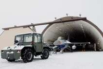 KUNSAN AIR BASE, Republic of Korea -- Members from the 35th Aircraft Maintenance Unit tow an F-16 Fighting Falcon into a hangar Dec. 18. The 35 AMU members moved the F-16 out of the weather to perform maintenance and continue their mission.  (U.S. Air Force photo by/Senior Airman Jonathan Steffen)