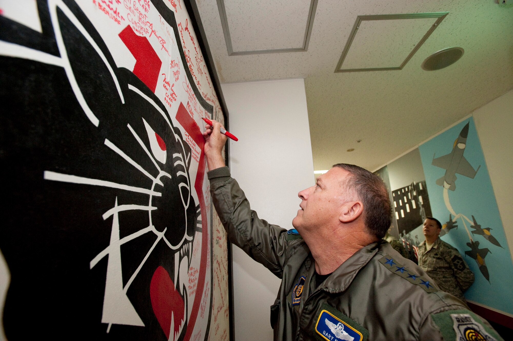 MISAWA CITY, Japan ? Gen. Gary North, Pacific Air Forces commander, signs his name to the 13th Aircraft Maintenance Unit's signature board Dec. 15 at Misawa Air Base, Japan. General North reminisced about his time as the 35th Operations Group commander at Misawa AB from 1994 to 1996. (U.S. Air Force photo/Staff Sgt. Samuel Morse)