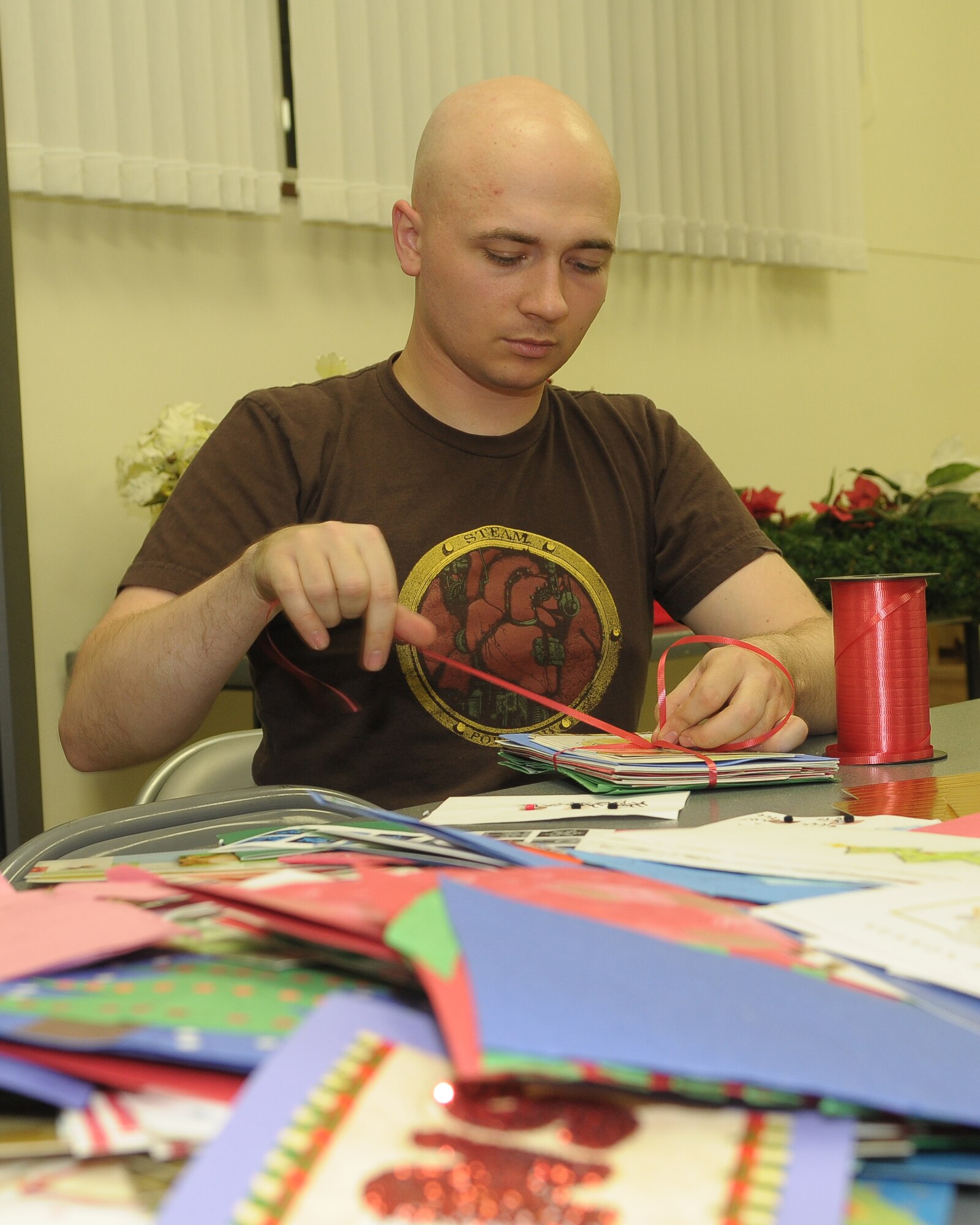 YOKOTA AIR BASE, Japan -- Airman 1st Class Guy Miller, 374th Civil Engineer Squadron, ties a ribbon around a stack of cards Dec. 17 during the "Holiday Mail for Heroes" campaign. The Yokota Chapter of the American Red Cross received more than 15,000 holiday cards eventually delivered to military members at Yokota and downrange. (U.S. Air Force photo/Airman 1st Class Sean Martin)