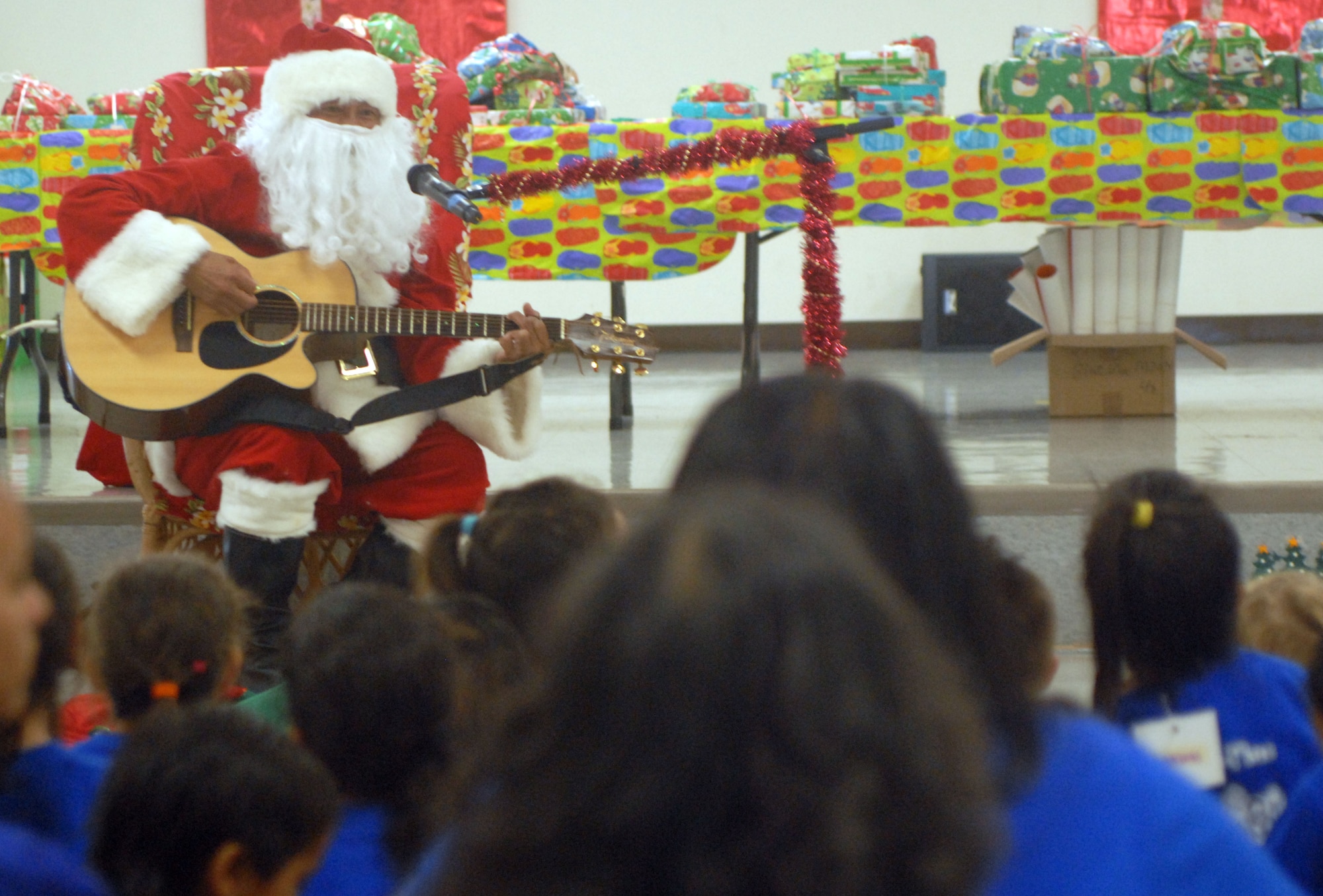 HICKAM AIR FORCE BASE, Hawaii - Ted Fabella, 15th Services Squadron, sings Christmas songs dressed as Santa Claus during the Head Start Holiday Party here, Dec. 17. The Annual event sponsored by the 15th Mission Support Group is held to support elementary school students with low income families. The event featured a movie, food, and gifts for the children donated by various organizations on base. (U.S. Air Force photo/Senior Airman Gustavo Gonzalez) 