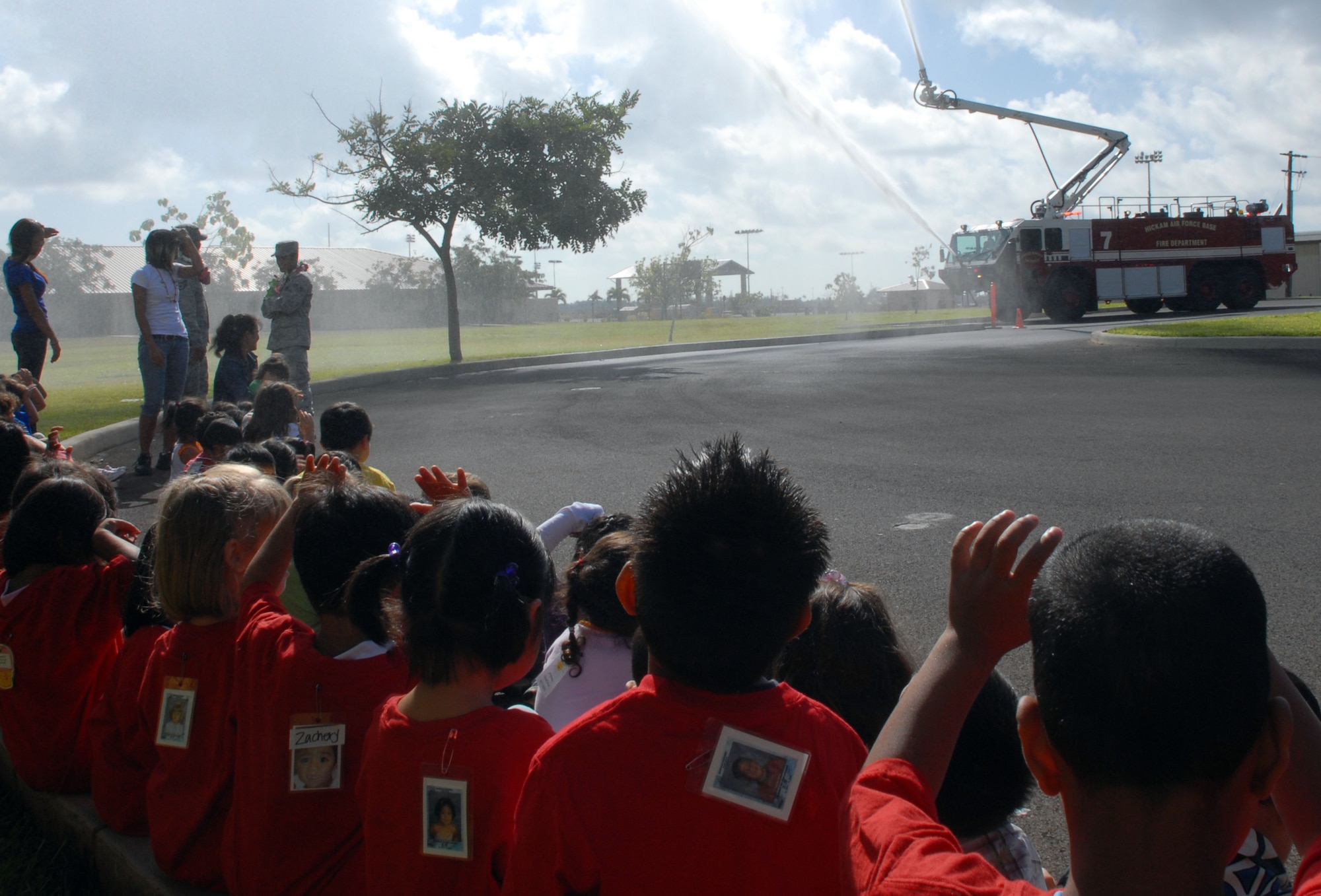 HICKAM AIR FORCE BASE, Hawaii - Fire fighters from the 15th Civil Engineer Squadron, puts on a water show during the Head Start Holiday Party here, Dec. 17. The Annual event sponsored by the 15th Mission Support Group is held to support elementary school students with low income families. The event featured a movie, food, and gifts for the children donated by various organizations on base. (U.S. Air Force photo/Senior Airman Gustavo Gonzalez) 
