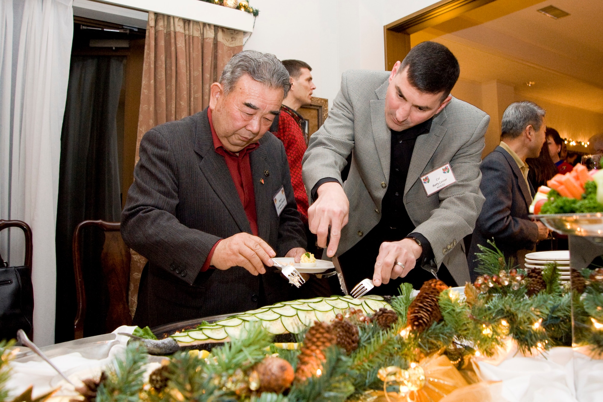 MISAWA AIR BASE, Japan -- Col. Barry Leister, 373rd Intelligence, Surveillance and Reconnaissance Group commander, slices a piece of poached salmon for Misawa City Mayor Kazumasa Taneichi Dec. 12 at the Stilwell residence. Col. David Stilwell, 35th Fighter Wing commander, held a social event for base leaders and local dignitaries at his house. The event offered an opportunity for informal conversation sharing American holiday culture and food. (U.S. Air Force photo/Staff Sgt. Samuel Morse)