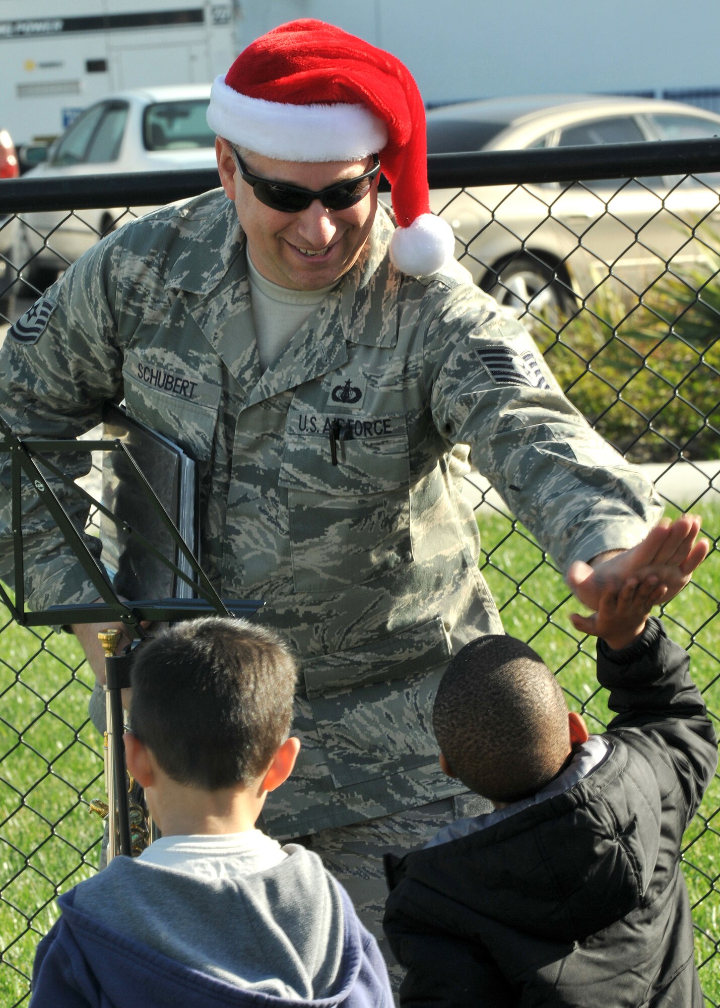 Master Sgt. Edward Schubert, a member of the United States Air Force Band of the Golden West’s brass band stationed at Travis Air Force Base, Calif., “high-fives” one of the children at the Child Development Center during their visit to Los Angeles AFB, Dec. 16.  The band performed holiday music at multiple venues and work areas throughout the base during their visit. (Photo by Atiba S. Copeland)