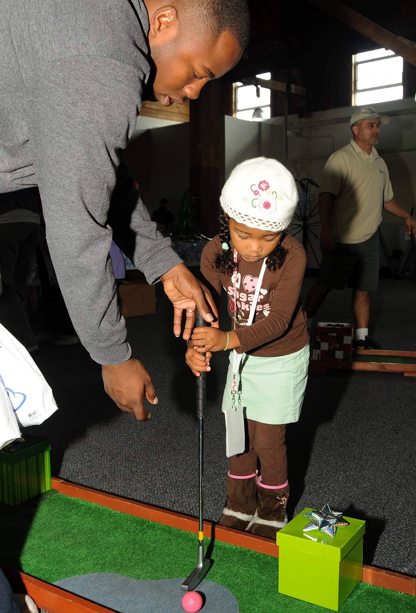 Lilie Donold gets some assistance from her father, Courtney, with her shots at a miniature golf game during the “Candy Land” children’s holiday celebration at Fort MacArthur Hall, San Pedro, Calif., Dec. 12.  Los Angeles Air Force Base’s Youth Programs provided food, fun and games for children ages 2-11. (Photo by Joe Juarez)