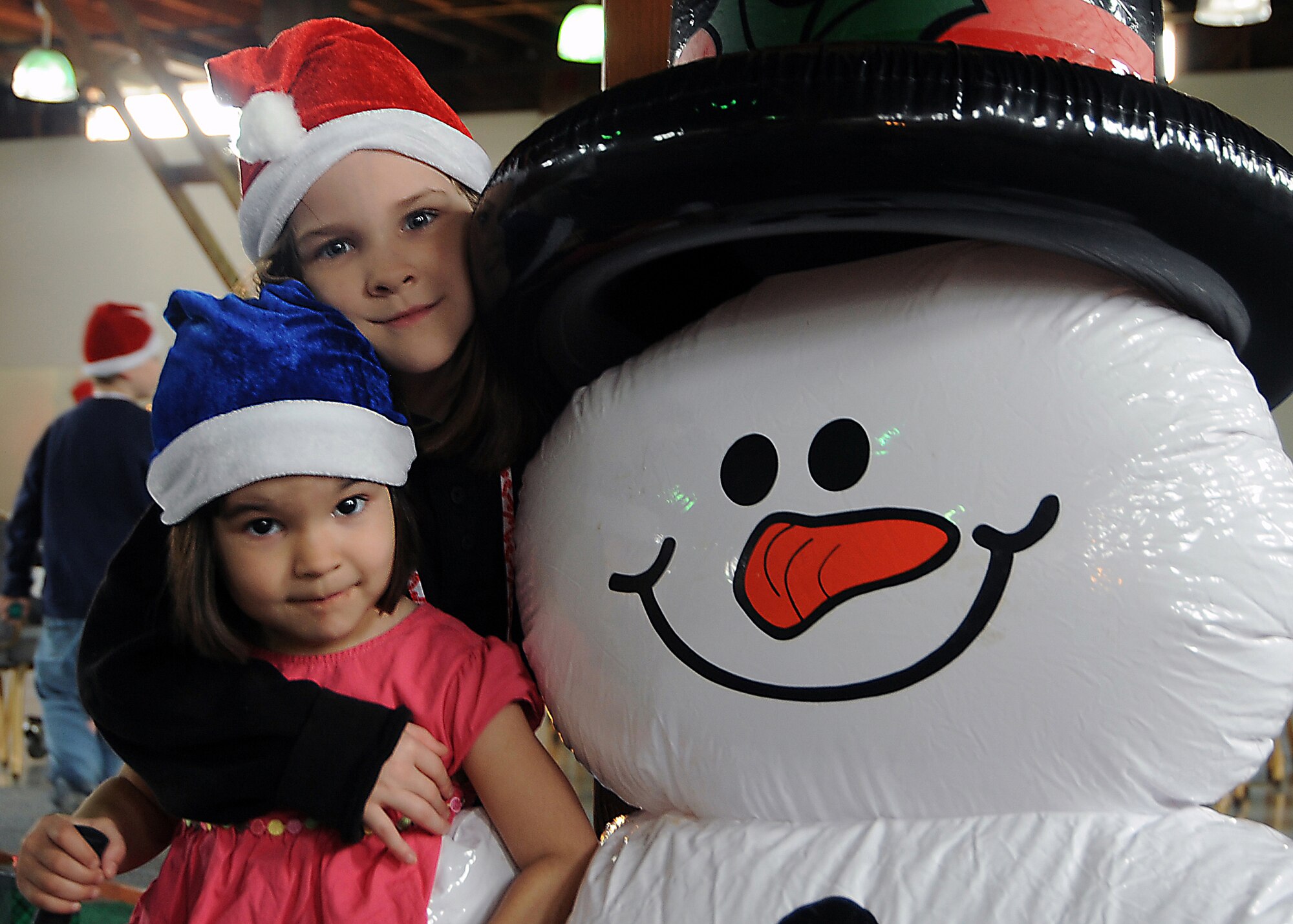 Athena and Ariel Ruiz pose with Frosty during the “Candy Land” children’s holiday celebration at Fort MacArthur Hall, San Pedro, Calif., Dec. 12. Los Angeles Air Force Base’s Youth Programs provided food, fun and games for children ages 2-11. (Photo by Joe Juarez)